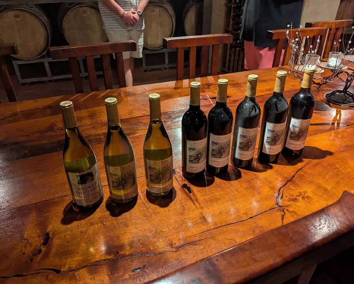 Wine tasting flight of Becker Vineyards reserve bottles lined up on a rustic wooden cellar table in Texas Hill Country