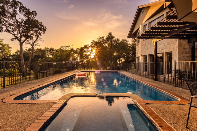 Golden sunset bursting through trees over the private pool and lodge at The Point CLTX overlooking Canyon Lake