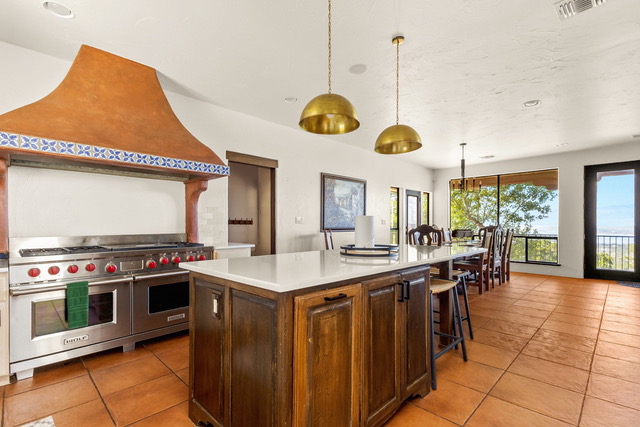 Gourmet open lodge kitchen with custom island, brass pendant lights, commercial Wolf range, and dining room overlooking Canyon Lake