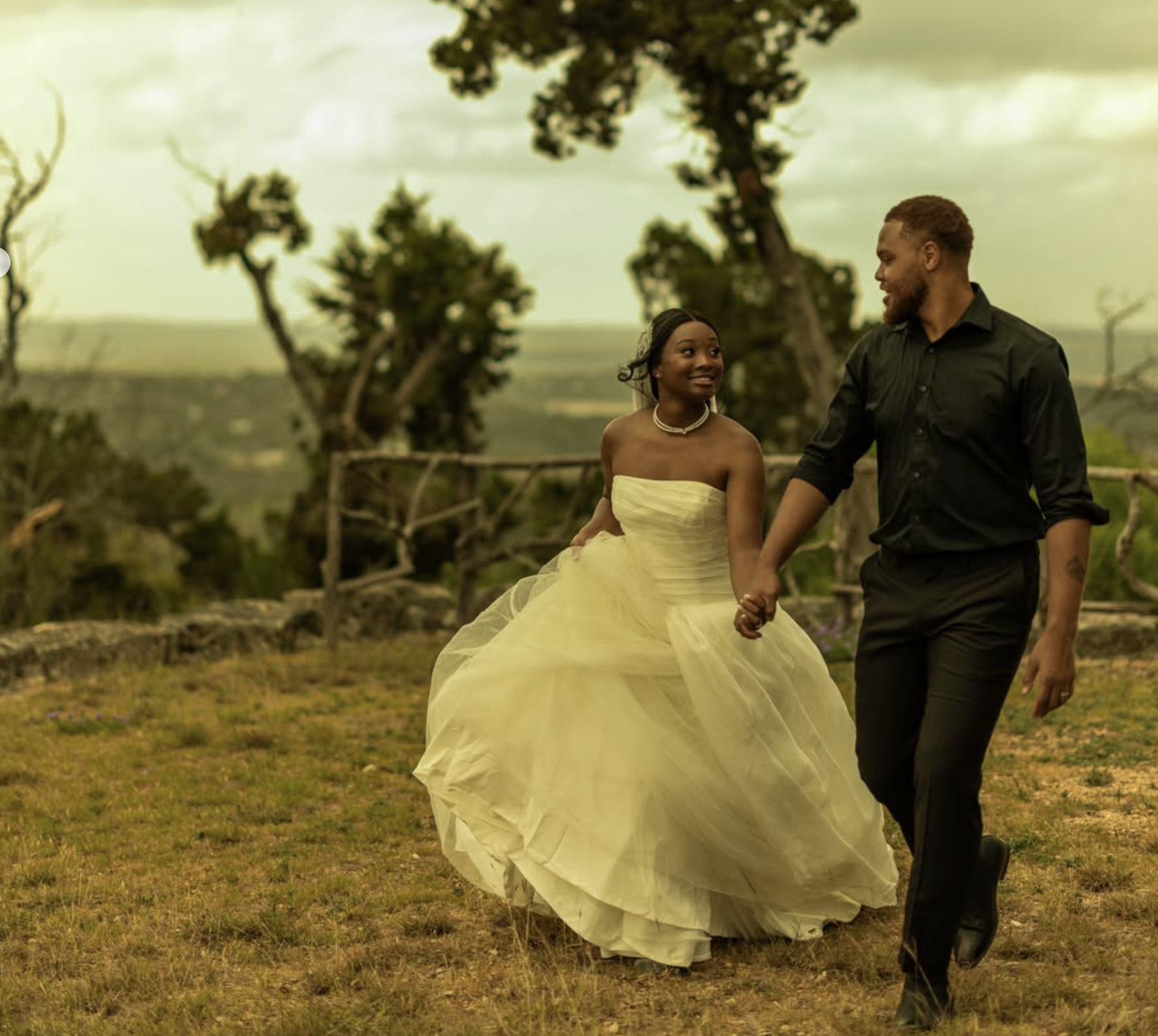 Bride and groom walking hand in hand across the grounds with panoramic Hill Country views at The Point CLTX