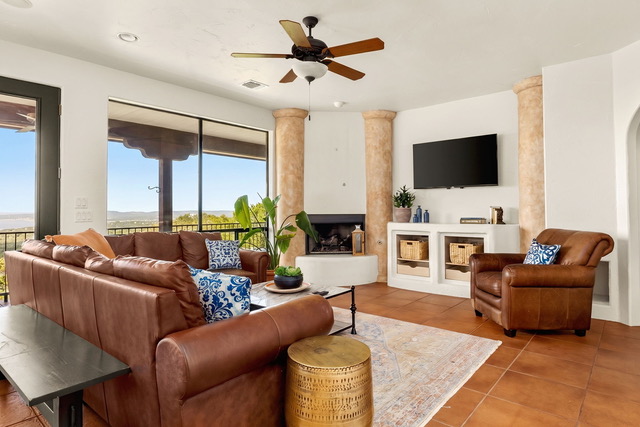 Spacious lodge living room with leather sectional, fireplace, TV, and panoramic lake view balcony windows at The Point CLTX