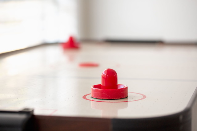 Air hockey table with red puck and paddles ready for friendly tournaments during retreats and reunions
