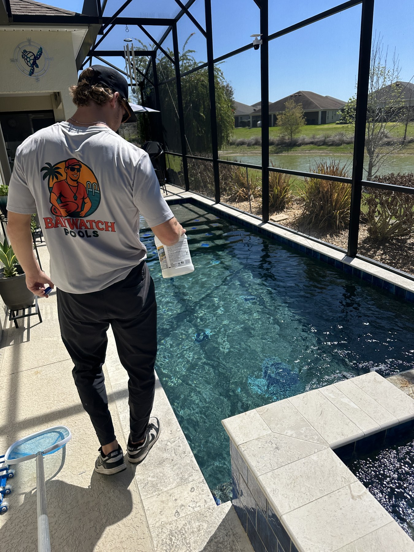 Baywatch Pools technician standing beside a client's swimming pool