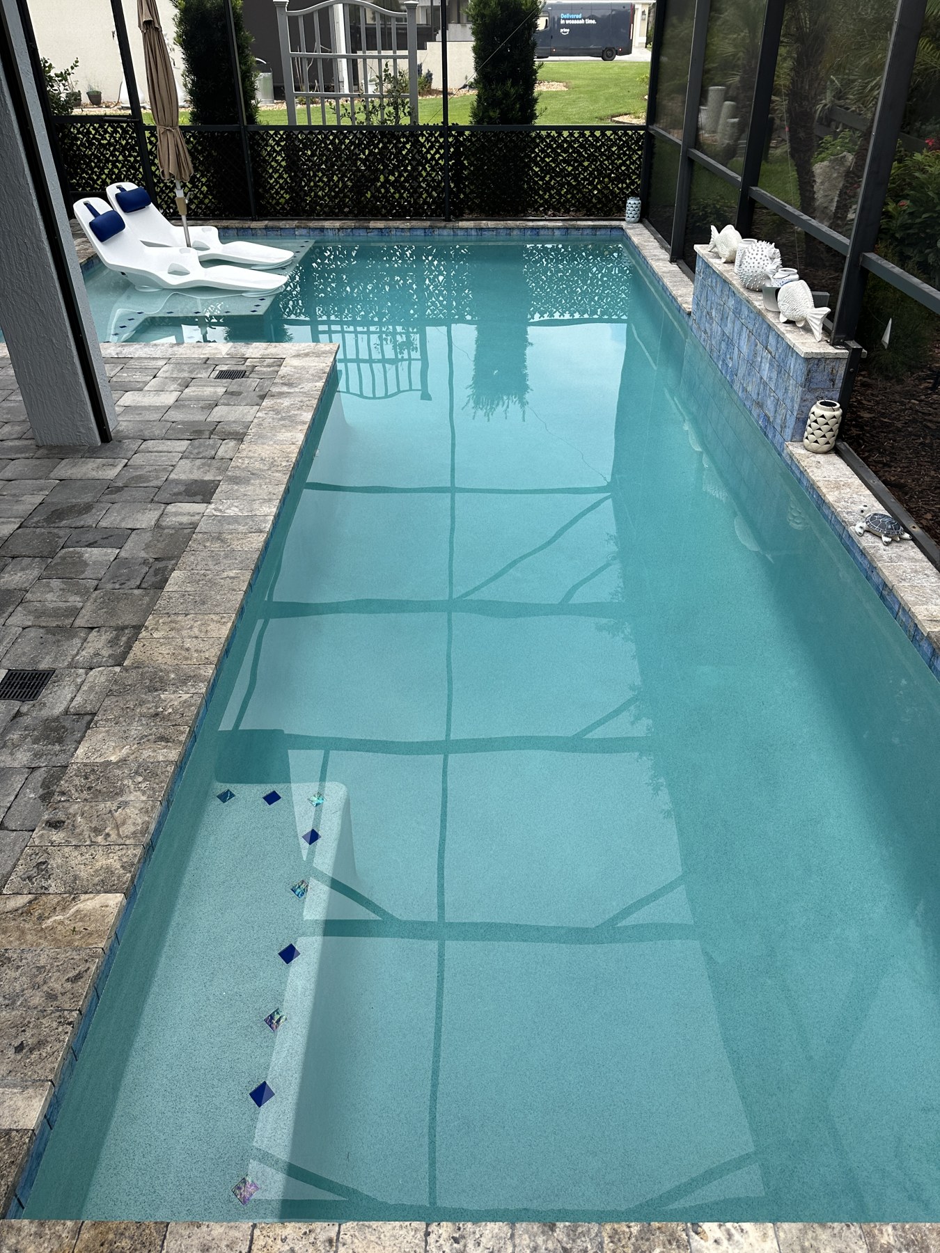 Crystal clear lap pool with sun loungers and paver patio