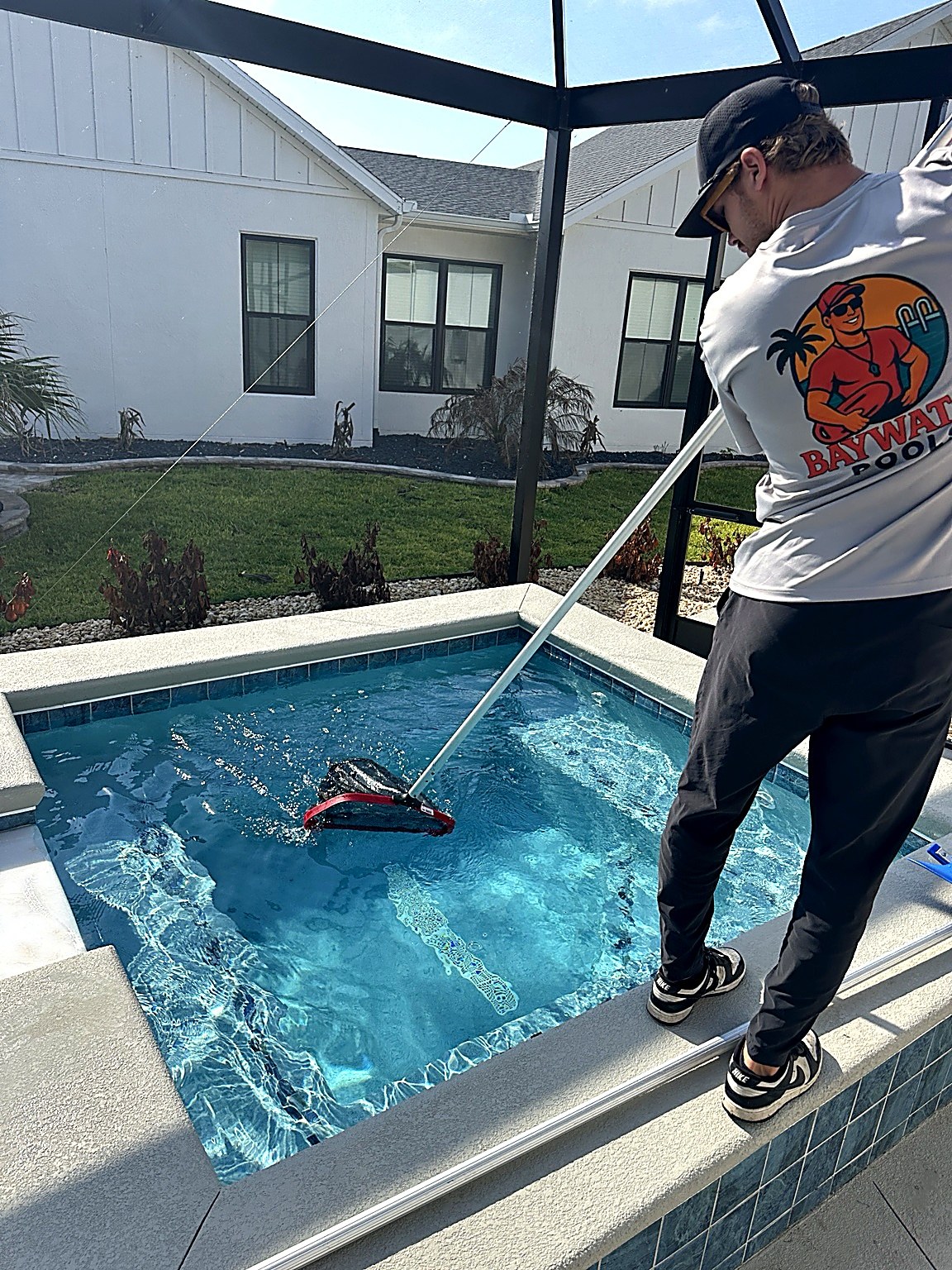 Pool technician skimming and cleaning a residential pool
