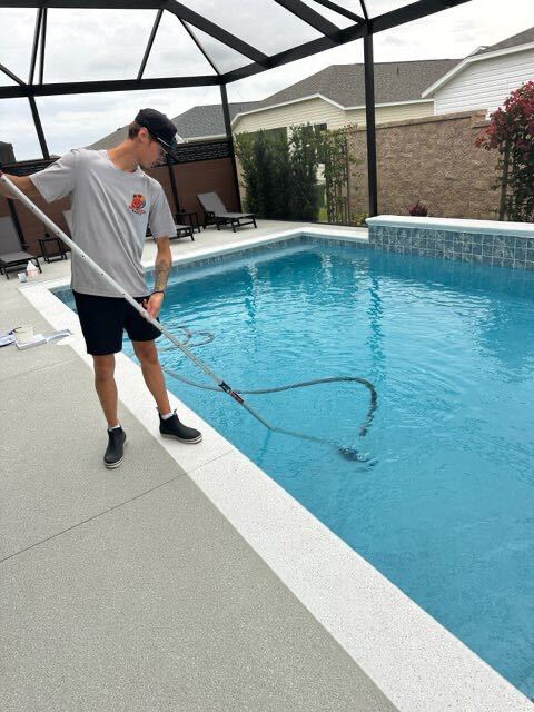 Baywatch Pools technician vacuuming pool floor with manual vacuum pole