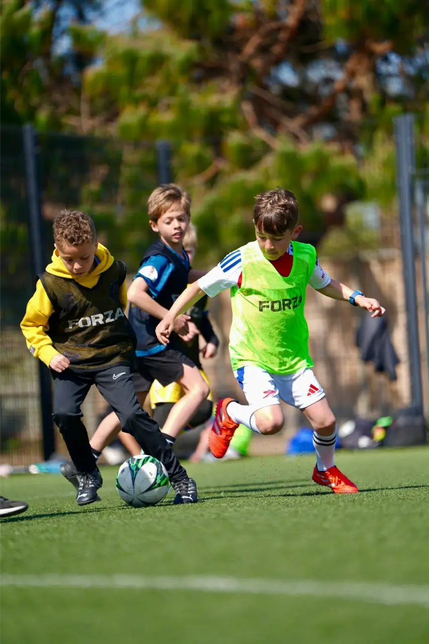 Children actively competing for the ball during youth football training in Esher