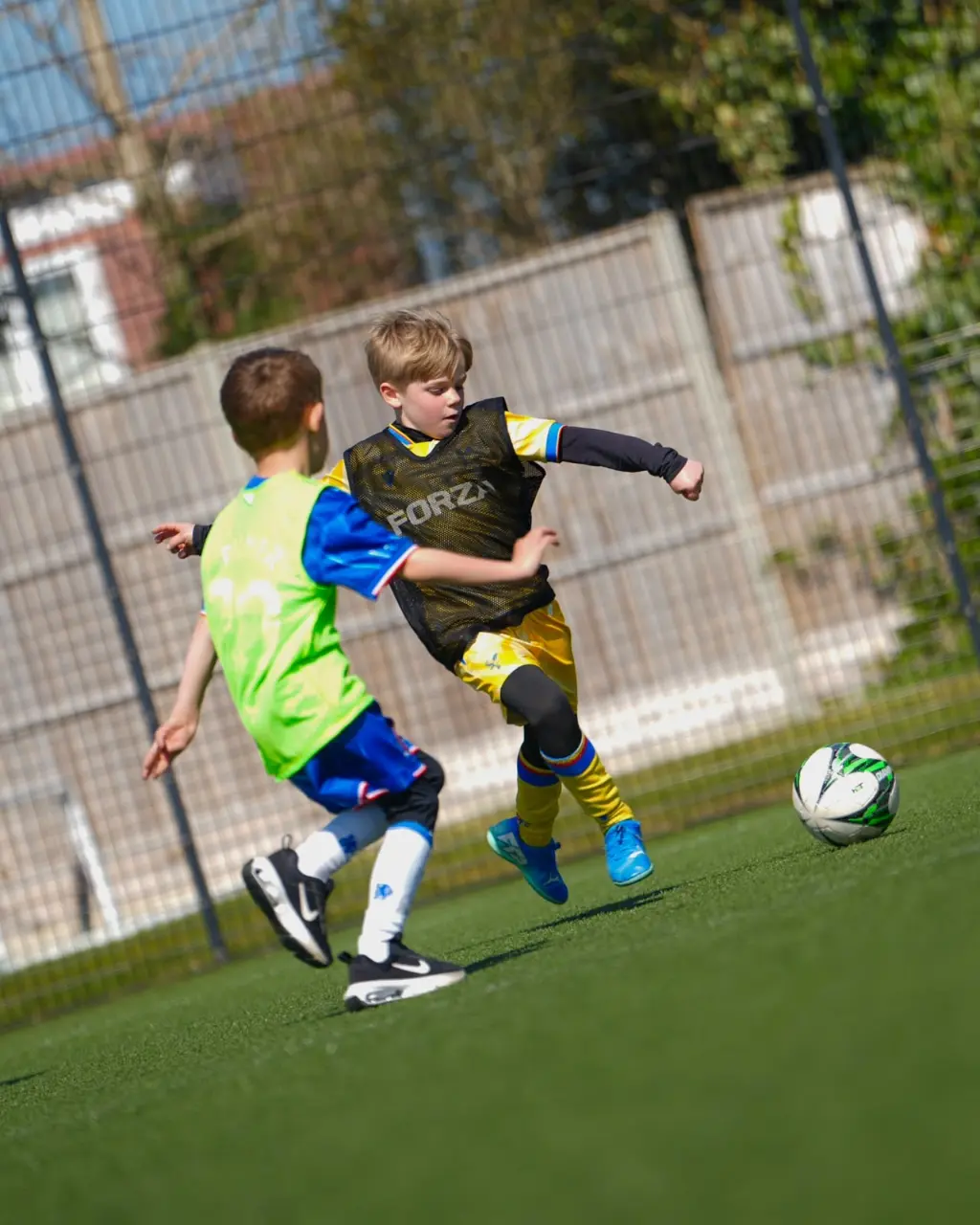 Young players training and tackling during football coaching in Esher