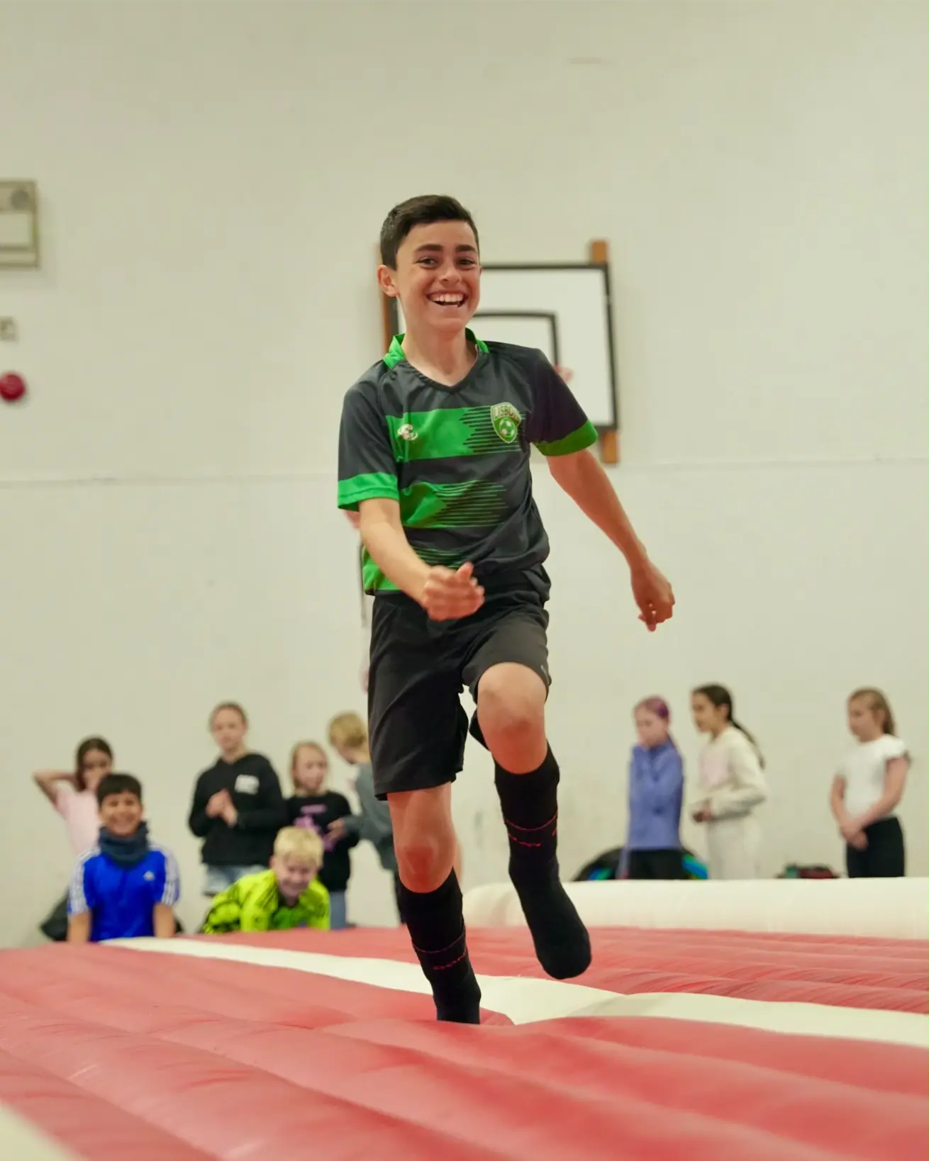 Young boy laughing and running happily on an inflatable bounce track during a sports session in Esher