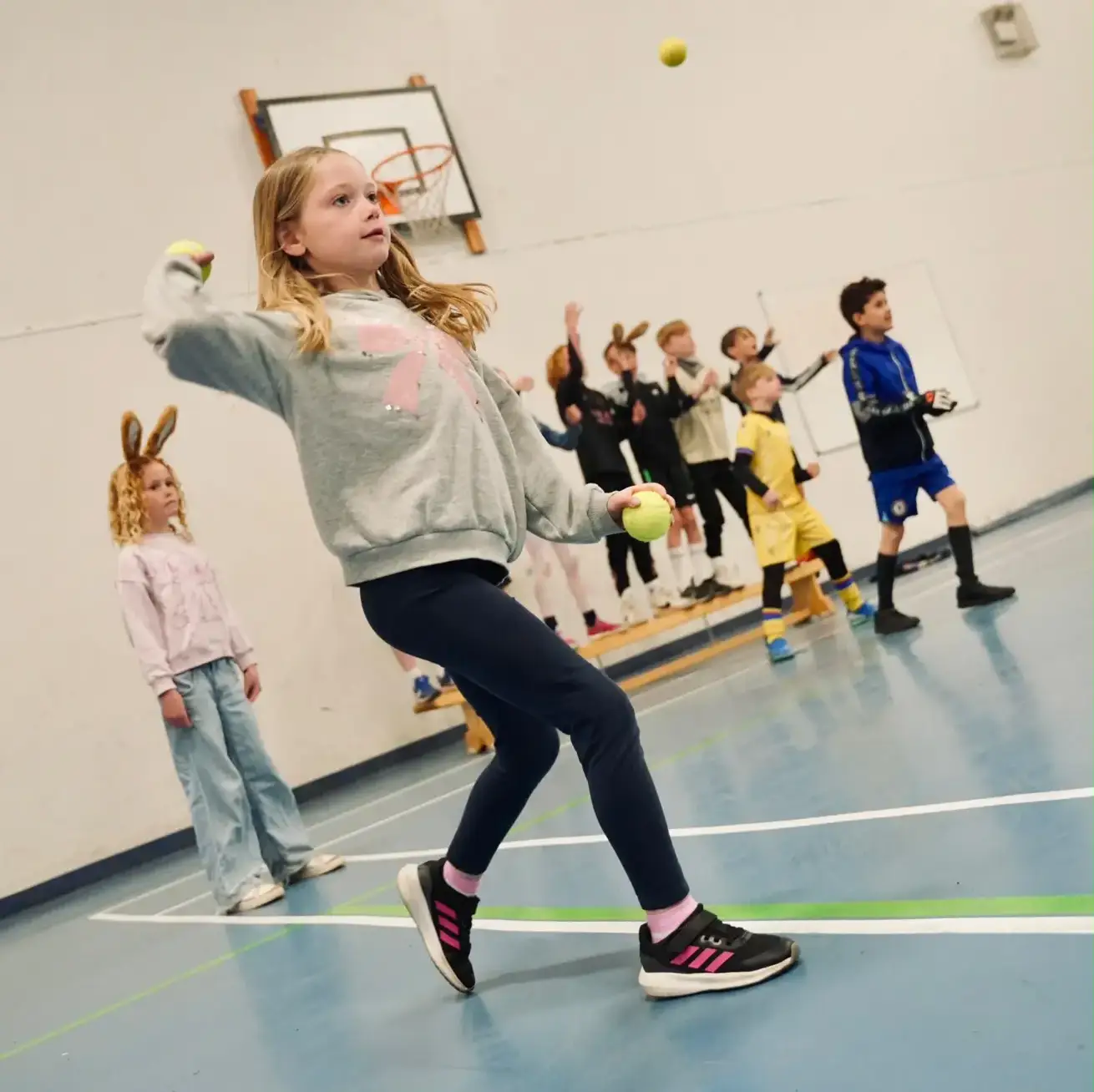 Young girl throwing a ball during an active holiday camp sports session in Esher