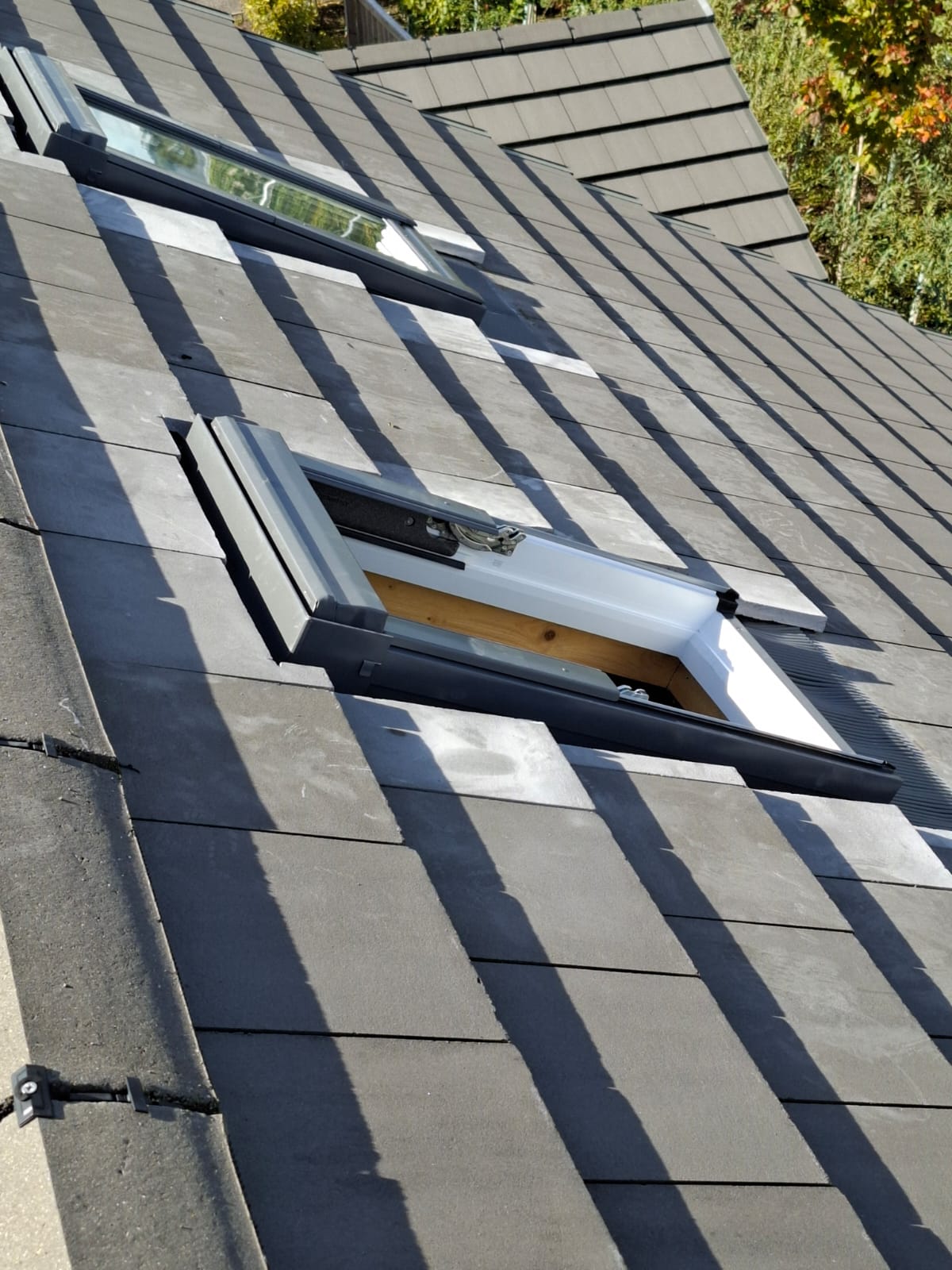 Fitted opening Velux roof window with weather-tight flashing on concrete tile roof by Smart Roofing Glasgow