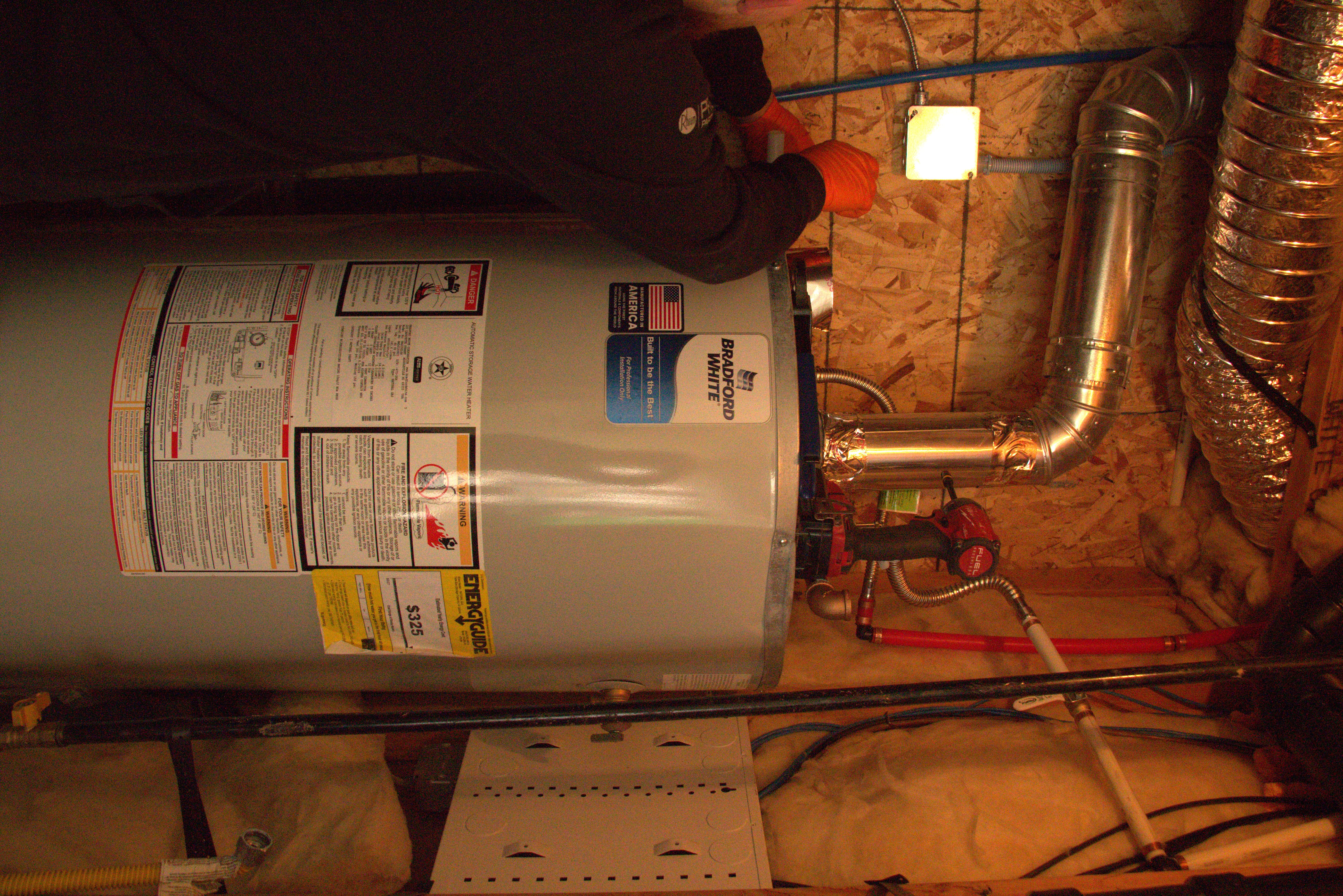 Green Line technician installing and connecting flue venting and gas piping on a new Bradford White water heater in Utah