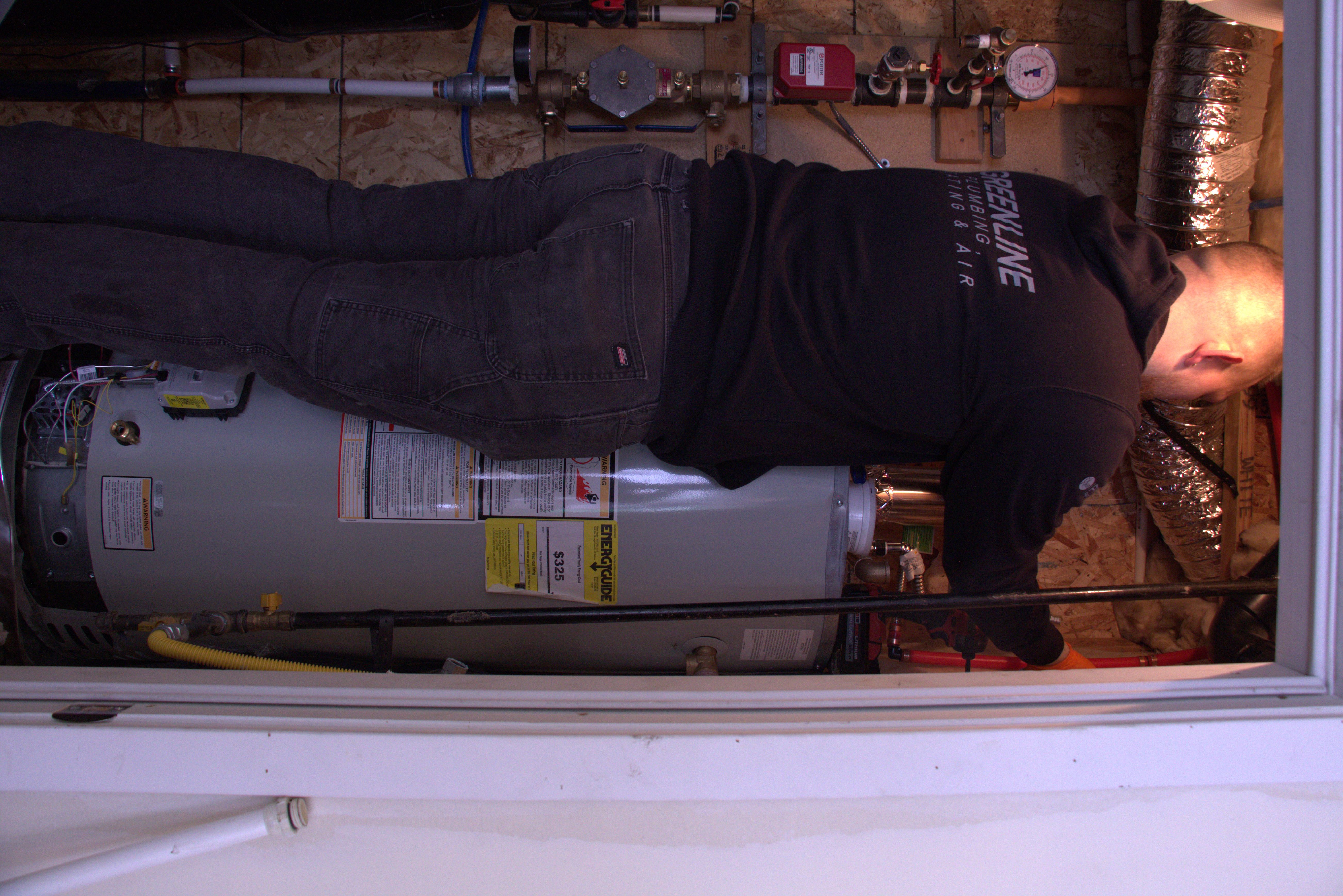 Licensed Green Line plumber diagnosing and installing a water heater in a Utah home mechanical room