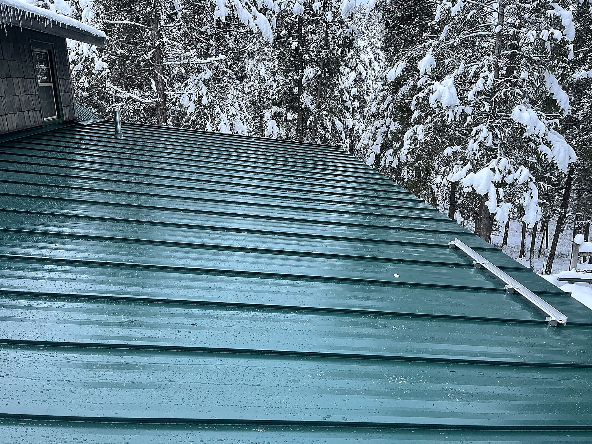 Snow retention rail on a green metal roof after heavy snowfall, Flathead Valley, Montana