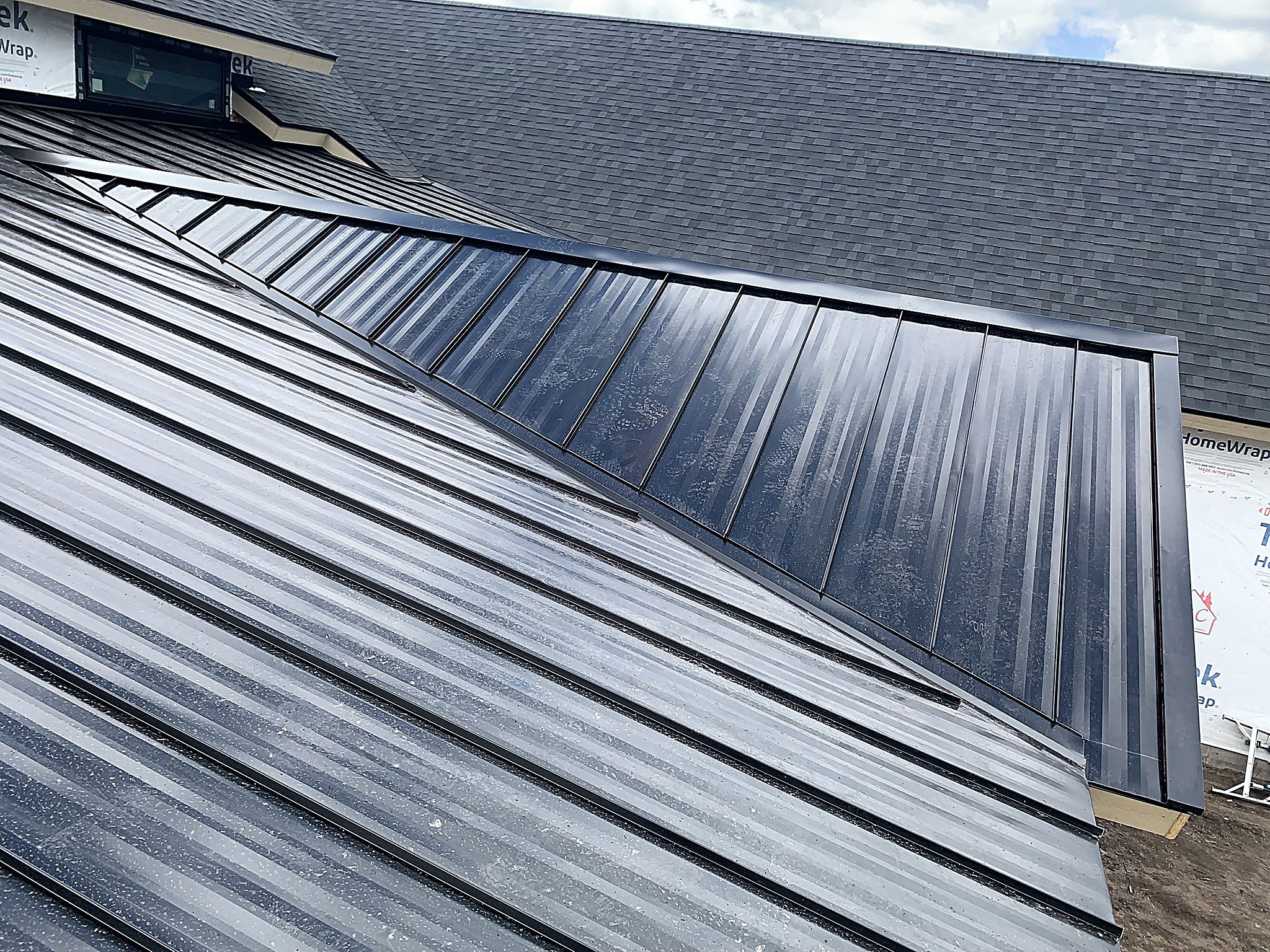 Standing seam metal roof panels meeting a shingle roof at a valley, Flathead Valley, Montana