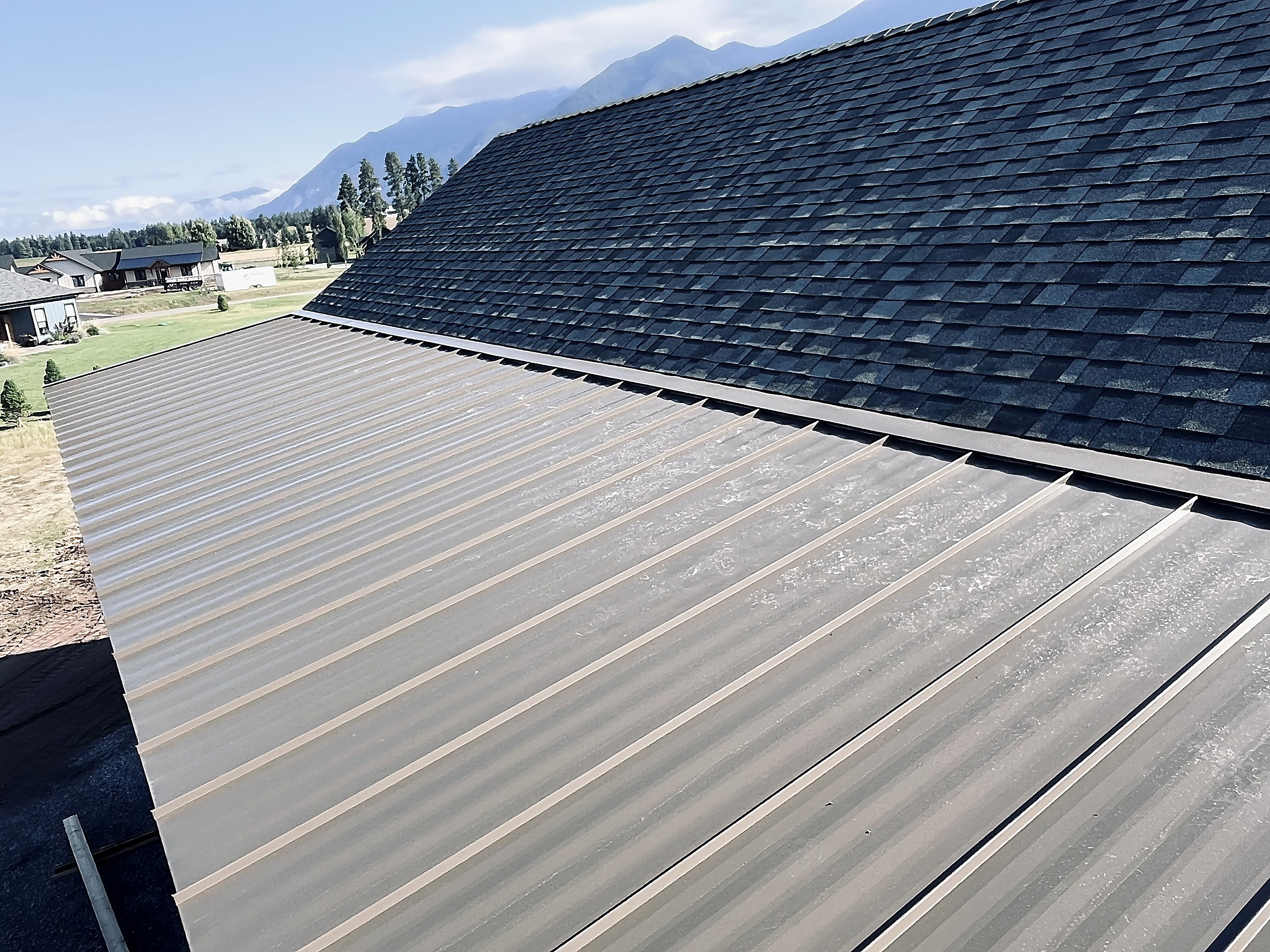 Standing seam metal roofing beside an asphalt shingle roof, Flathead Valley, Montana