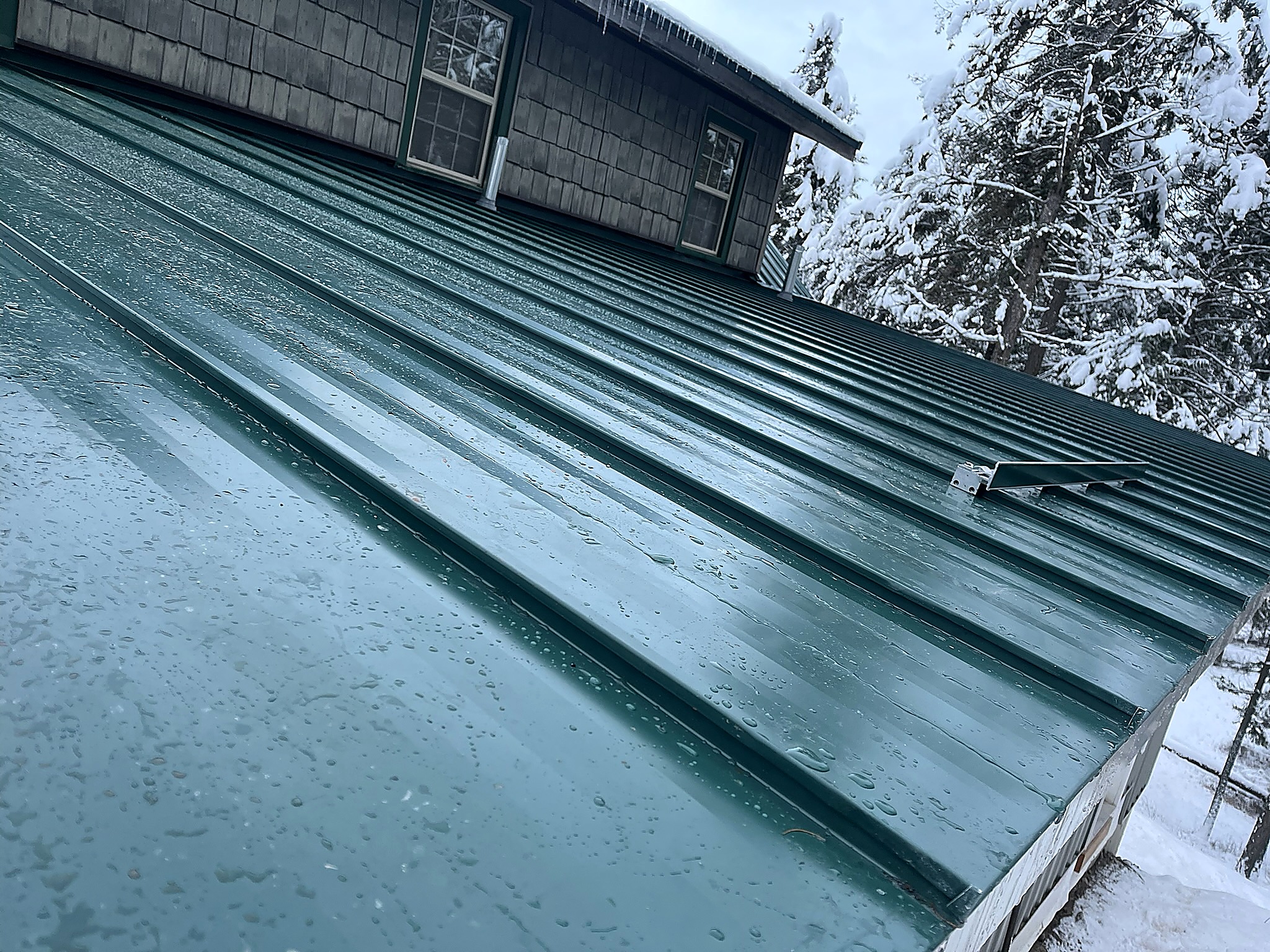 Snow guard bracket on a green metal roof in the Flathead Valley, Montana