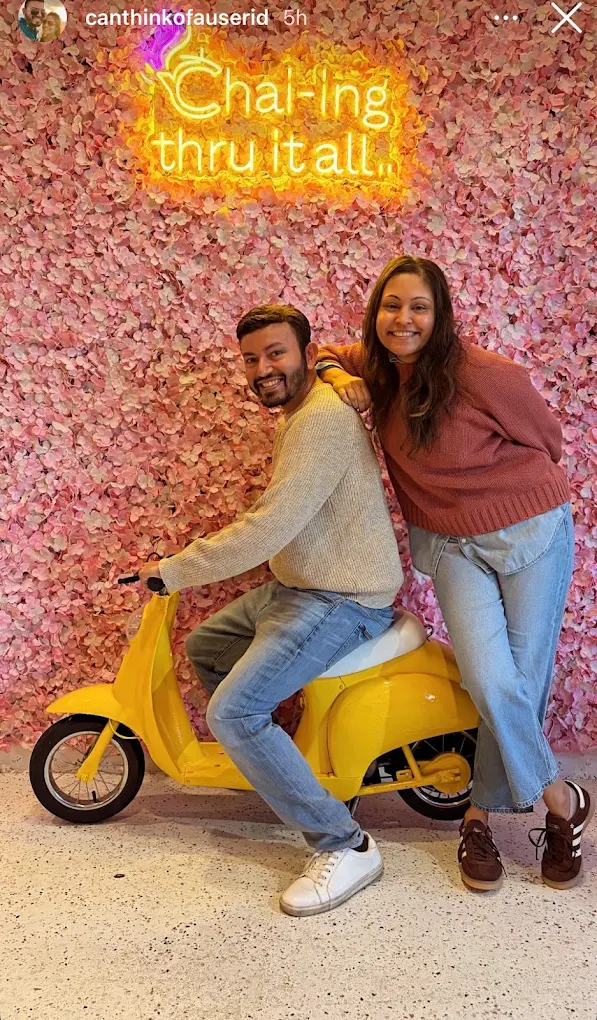 Happy guests on yellow scooter by Chai-ing thru it all neon wall