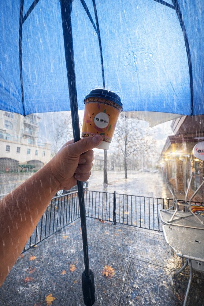 Chai & Co. warm chai cup in the rain under umbrella