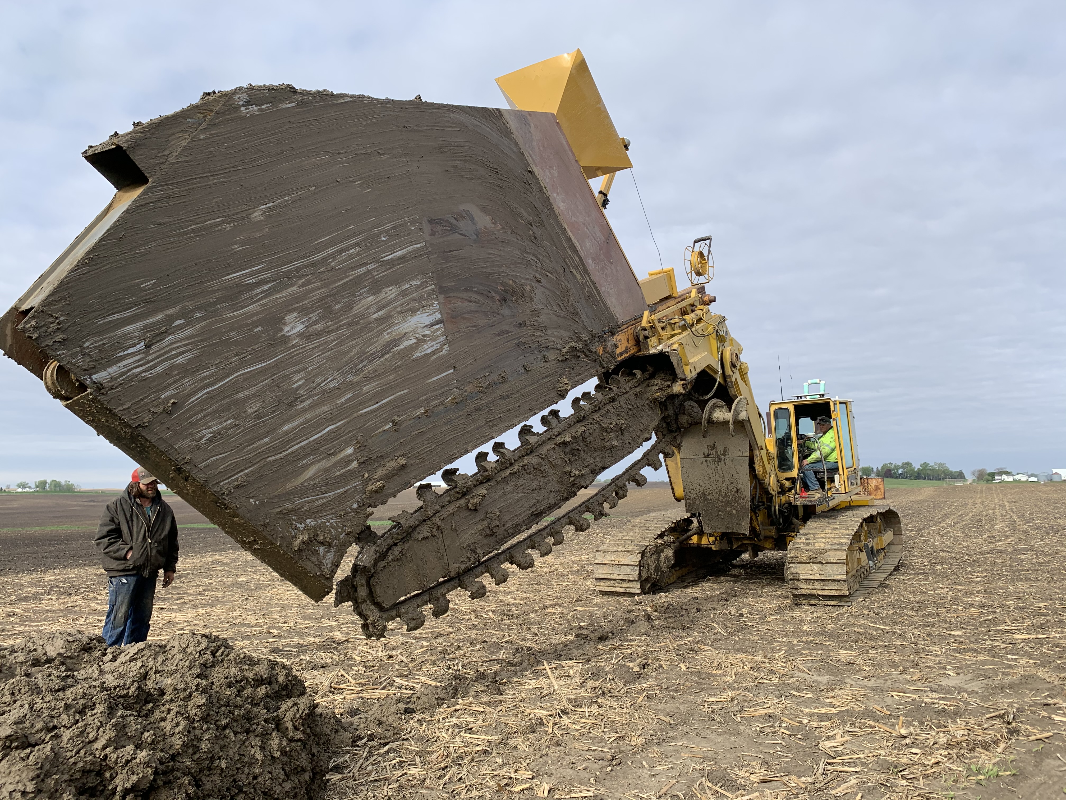 Heavy-duty tracked trencher cutting deep through Iowa soil.
