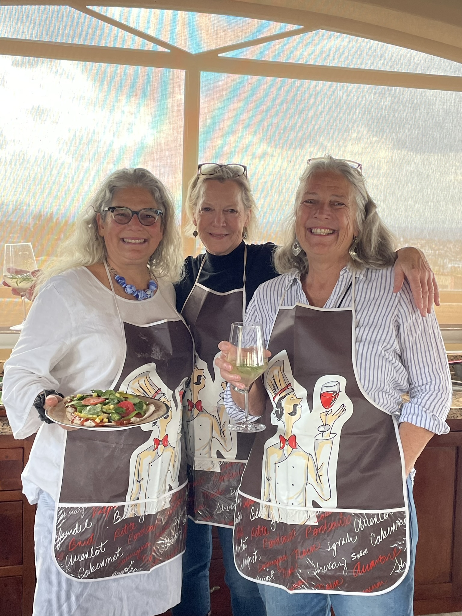 Friends celebrating on the rooftop terrace with homemade pizza, wine, and chef aprons