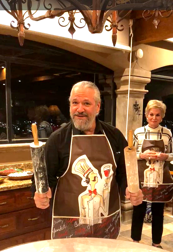 Guests wearing chef aprons holding rolling pins at a rooftop pizza-making party at Casa Grande