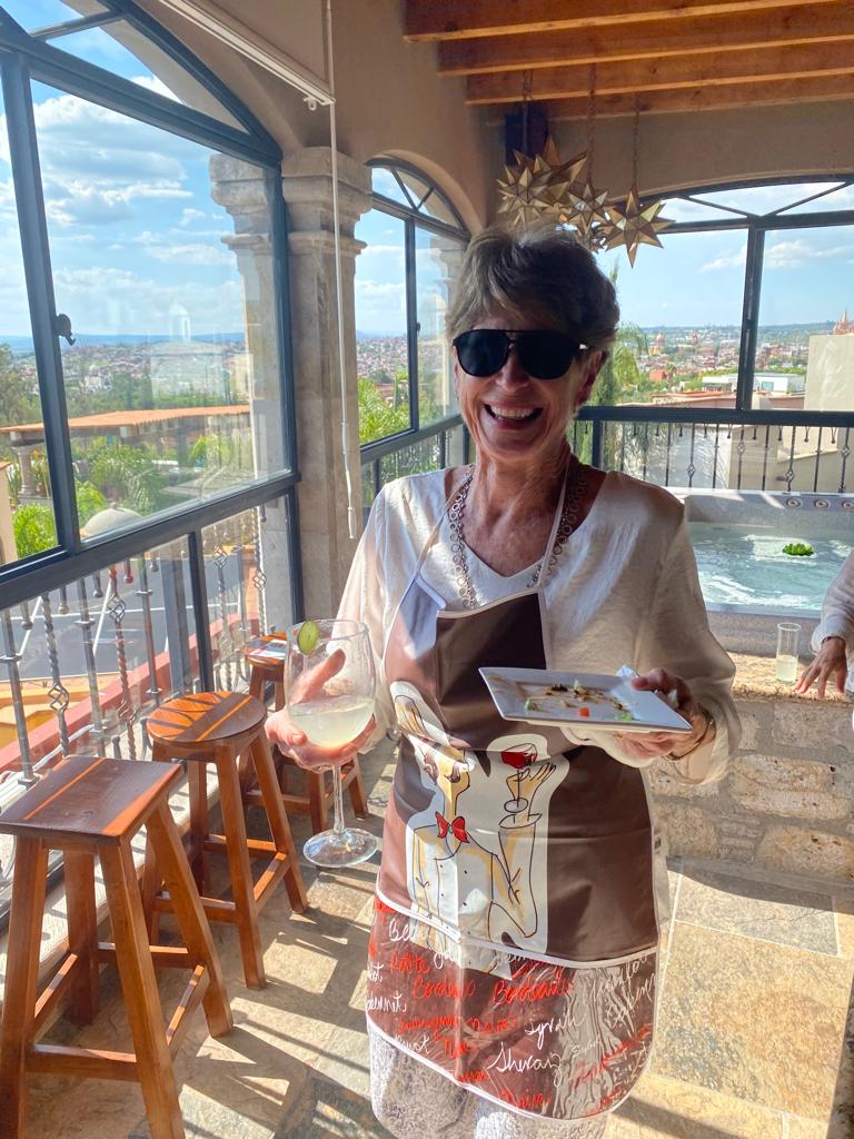 Smiling guest enjoying a cocktail and appetizers on the rooftop terrace overlooking San Miguel and the hot tub