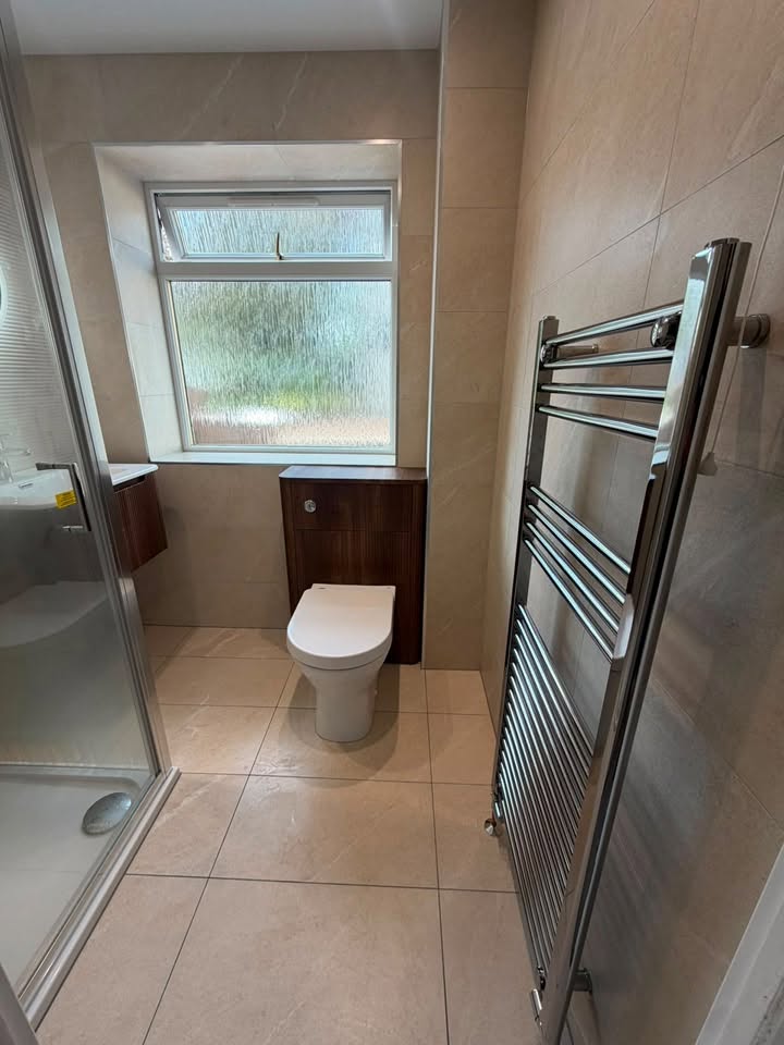 Warm stone-tiled ensuite with chrome towel rail and walnut vanity by MMA All Trades Dundee