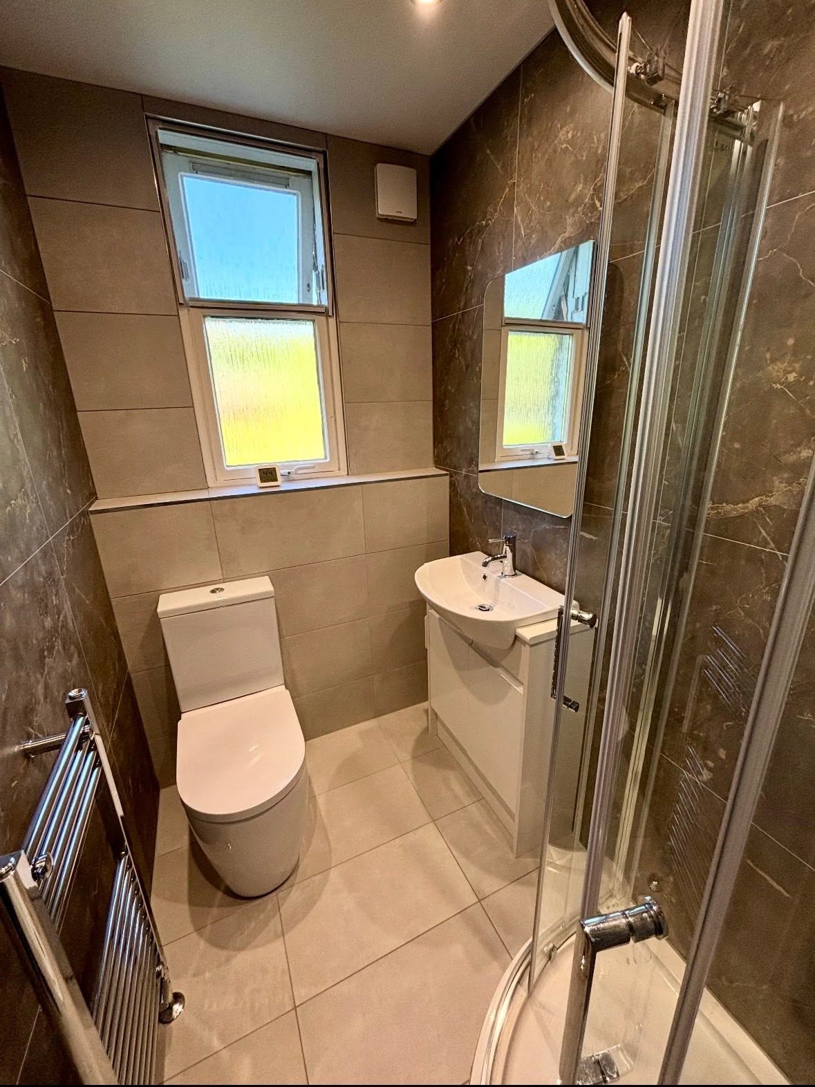 Marble-effect tiled ensuite bathroom with corner shower and modern vanity by MMA All Trades Dundee
