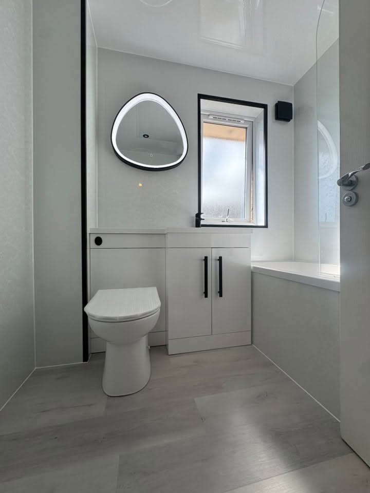 Modern white bathroom suite with pebble LED illuminated mirror and black trim by MMA All Trades Dundee
