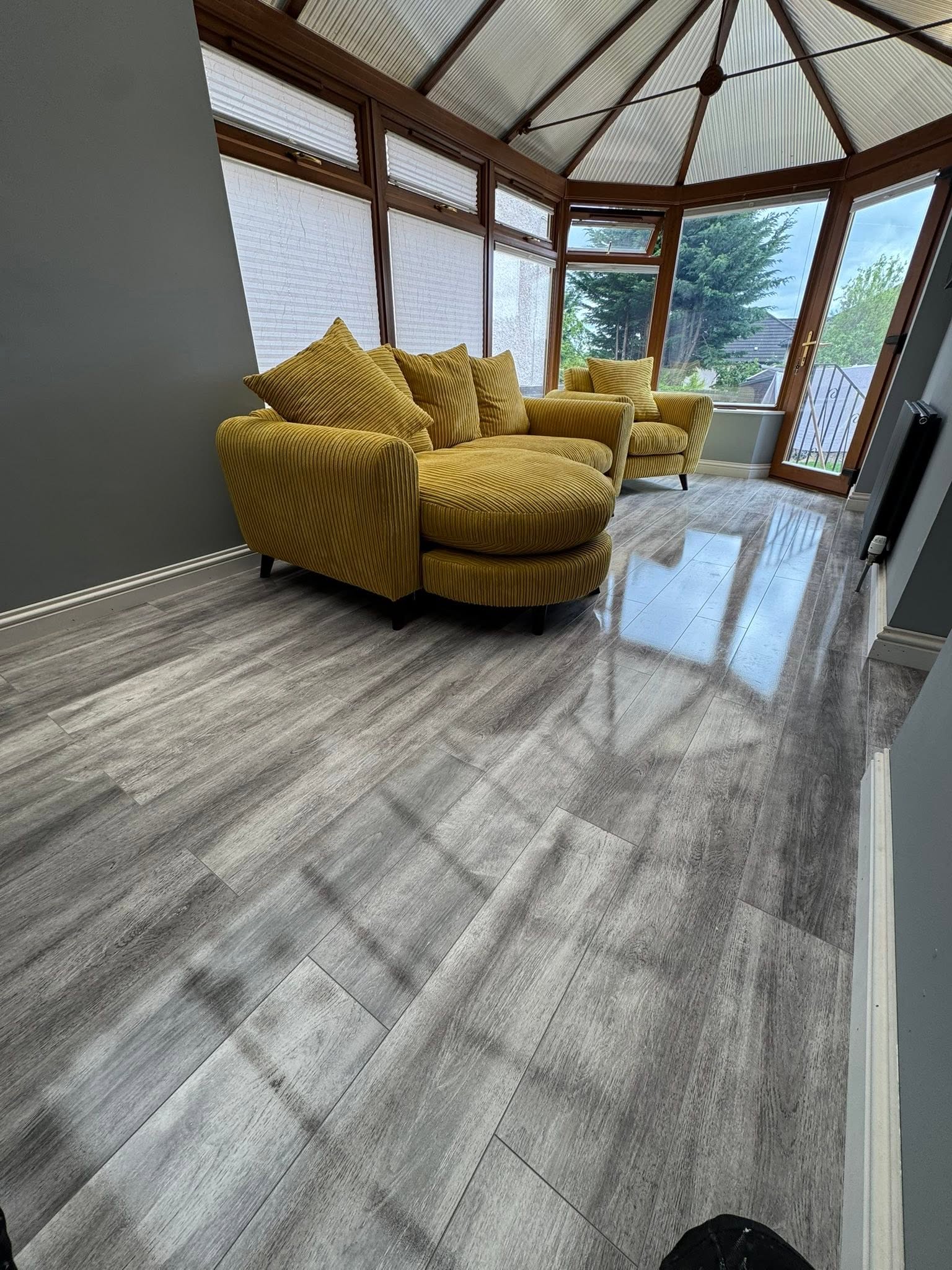 High gloss grey oak laminate flooring installation in sunroom by MMA All Trades Dundee