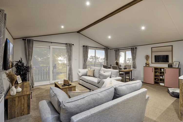 Spacious open-plan living room and dining area with vaulted ceiling and patio doors