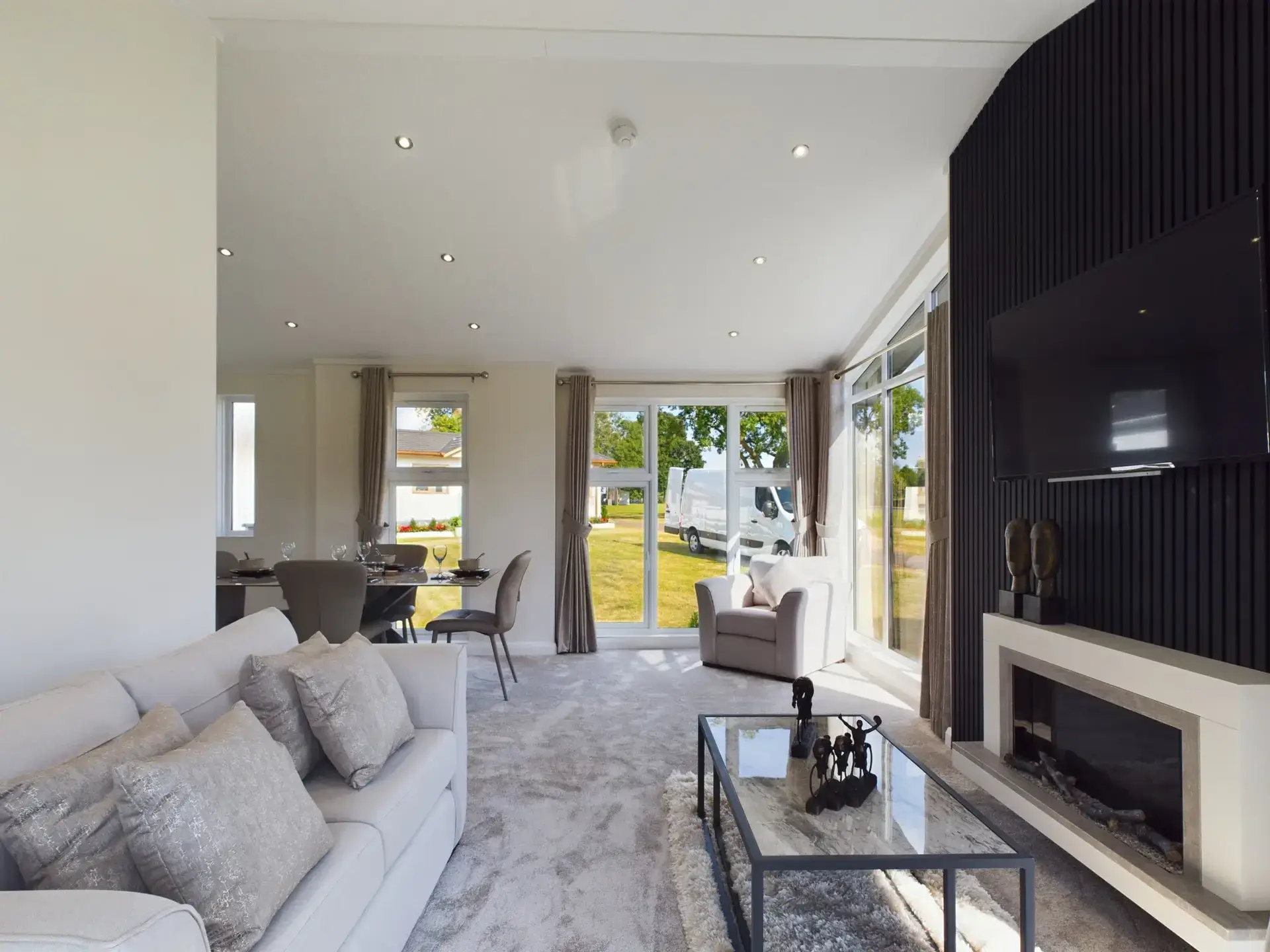 Modern lounge with slatted acoustic feature wall, fireplace, and countryside views