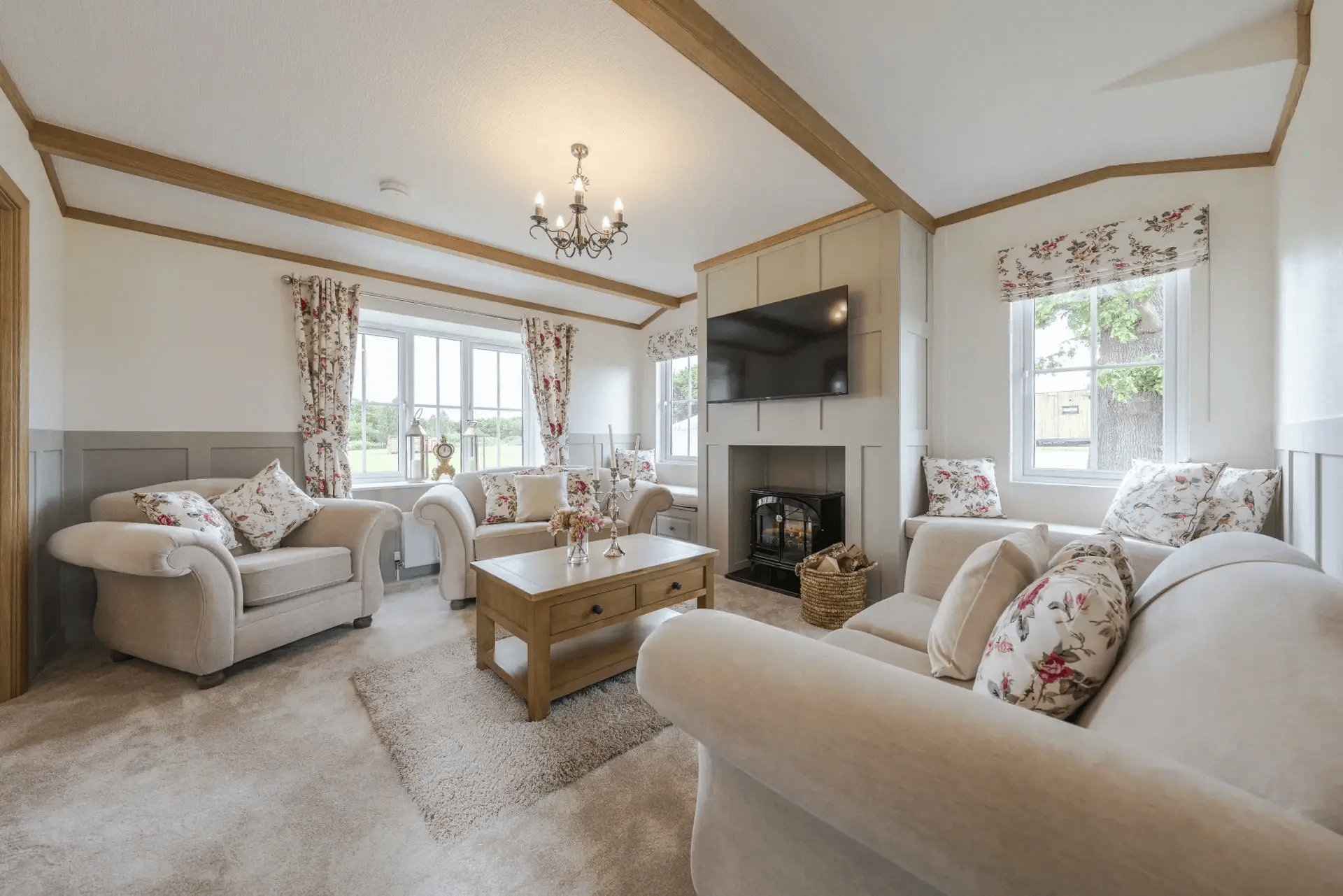 Cosy countryside lodge living room with exposed ceiling beams and log-burner style fireplace