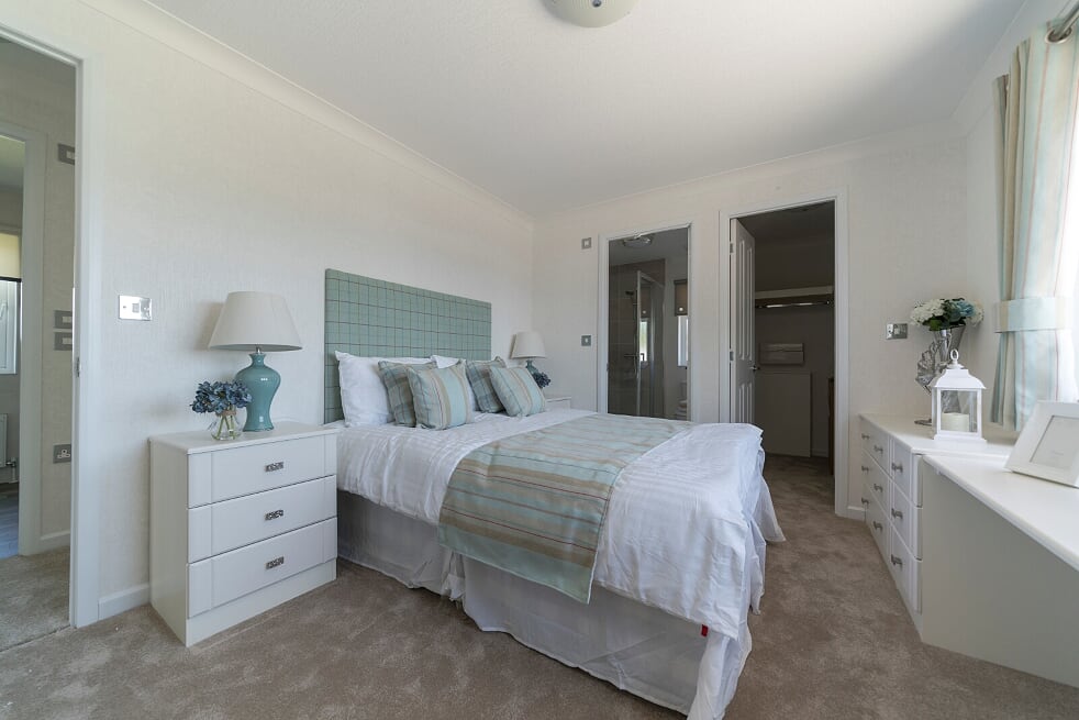 Bright double bedroom with sage green headboard, en-suite, and walk-in wardrobe