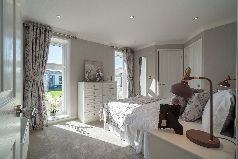 Master bedroom suite with fitted furniture, floral curtains, and en-suite access