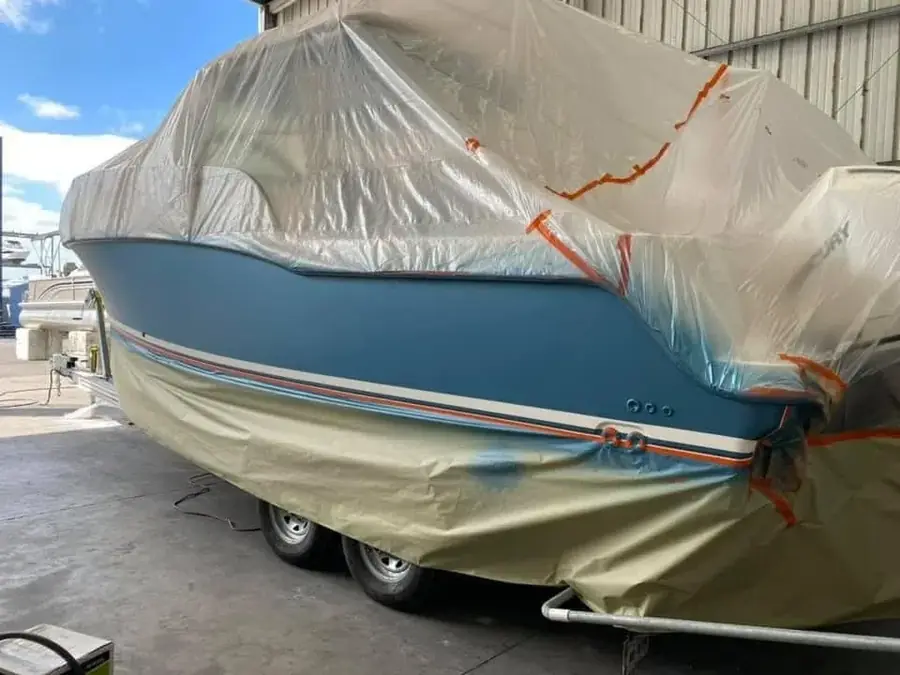 Boat masked and prepared for repainting and finish work