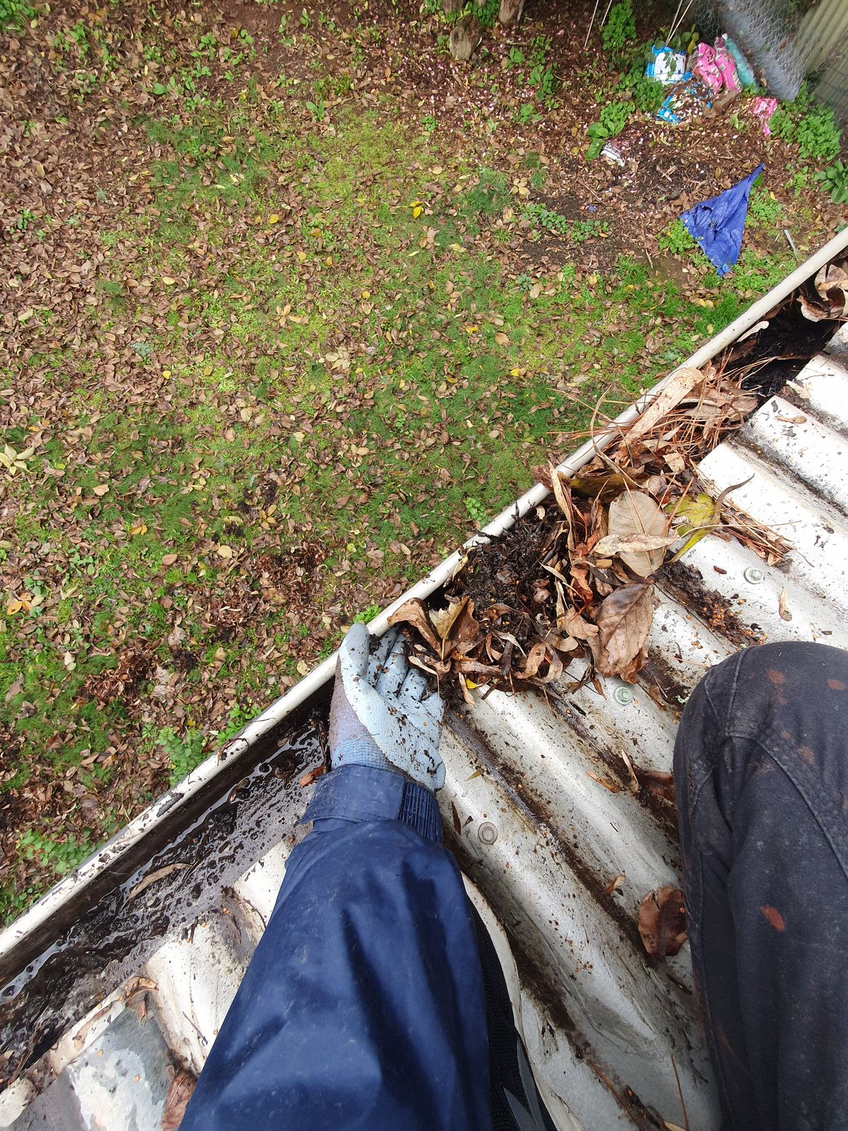 Machete Cleaning technician hand-clearing packed gutter debris in Kern County, CA