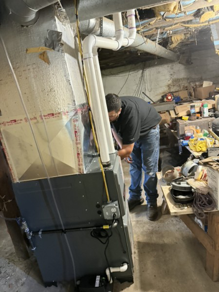 Austin Fancher commissioning an Amana furnace in the mechanical room