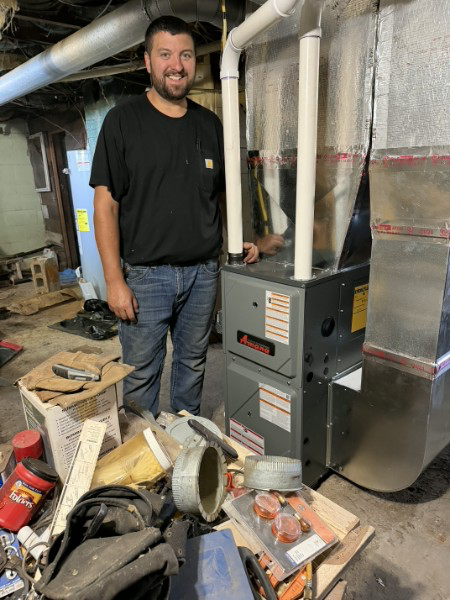 Austin Fancher beside an Amana high-efficiency furnace