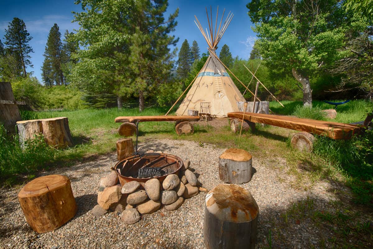 A teepee and fire pit by the river
