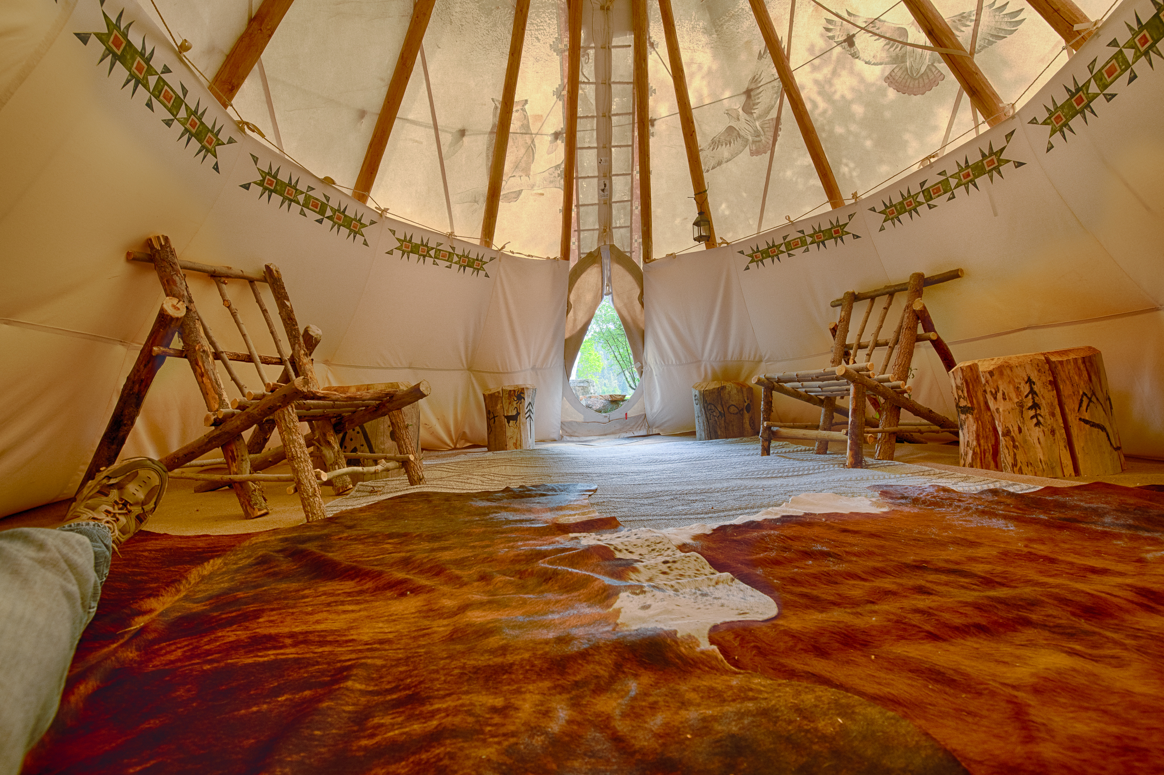 Glamping teepee interior with rugs and rustic log furniture