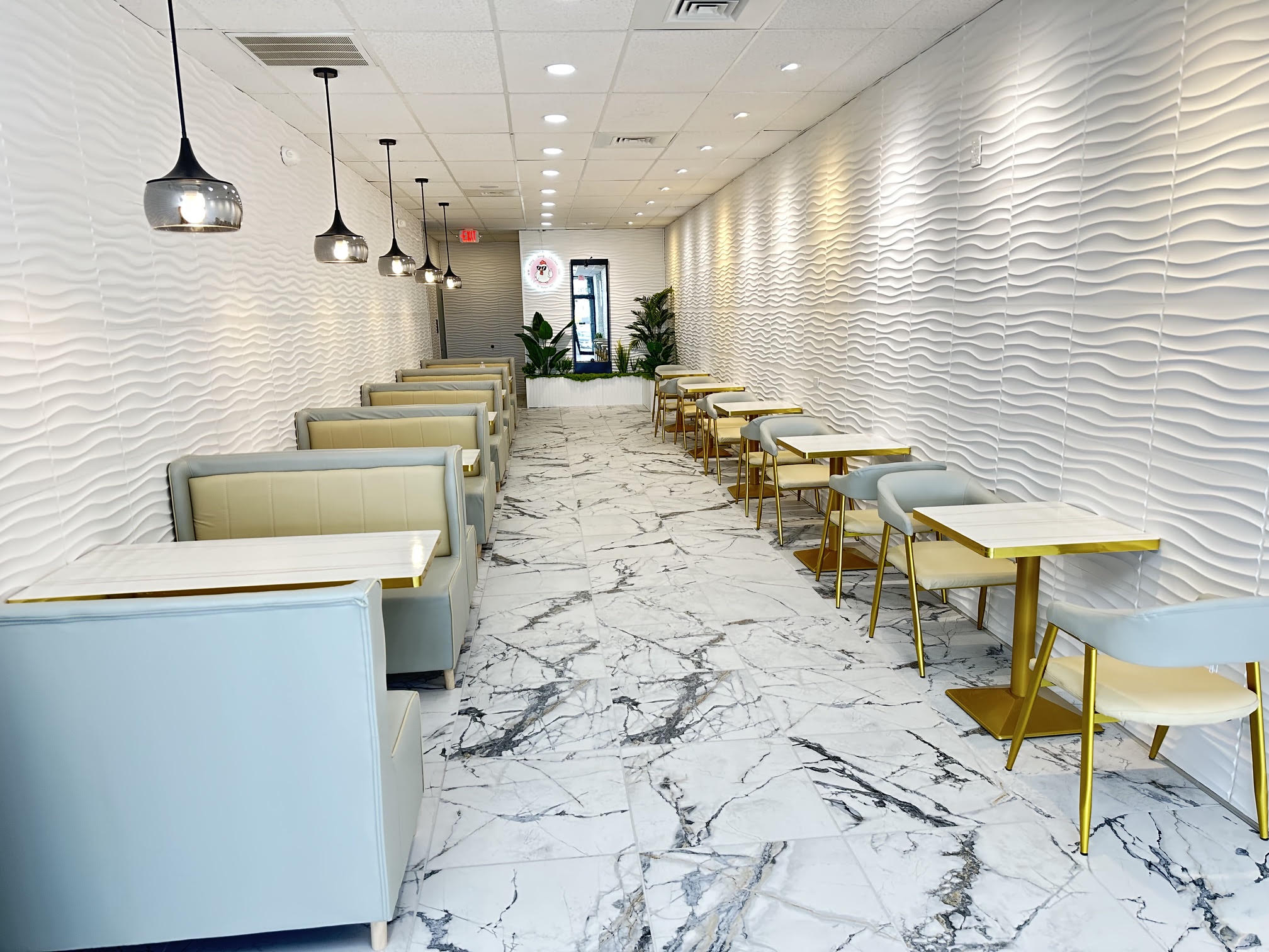 Bright modern white-and-pink dining room with booth seating, gold-accent tables and smoked-glass pendant lights