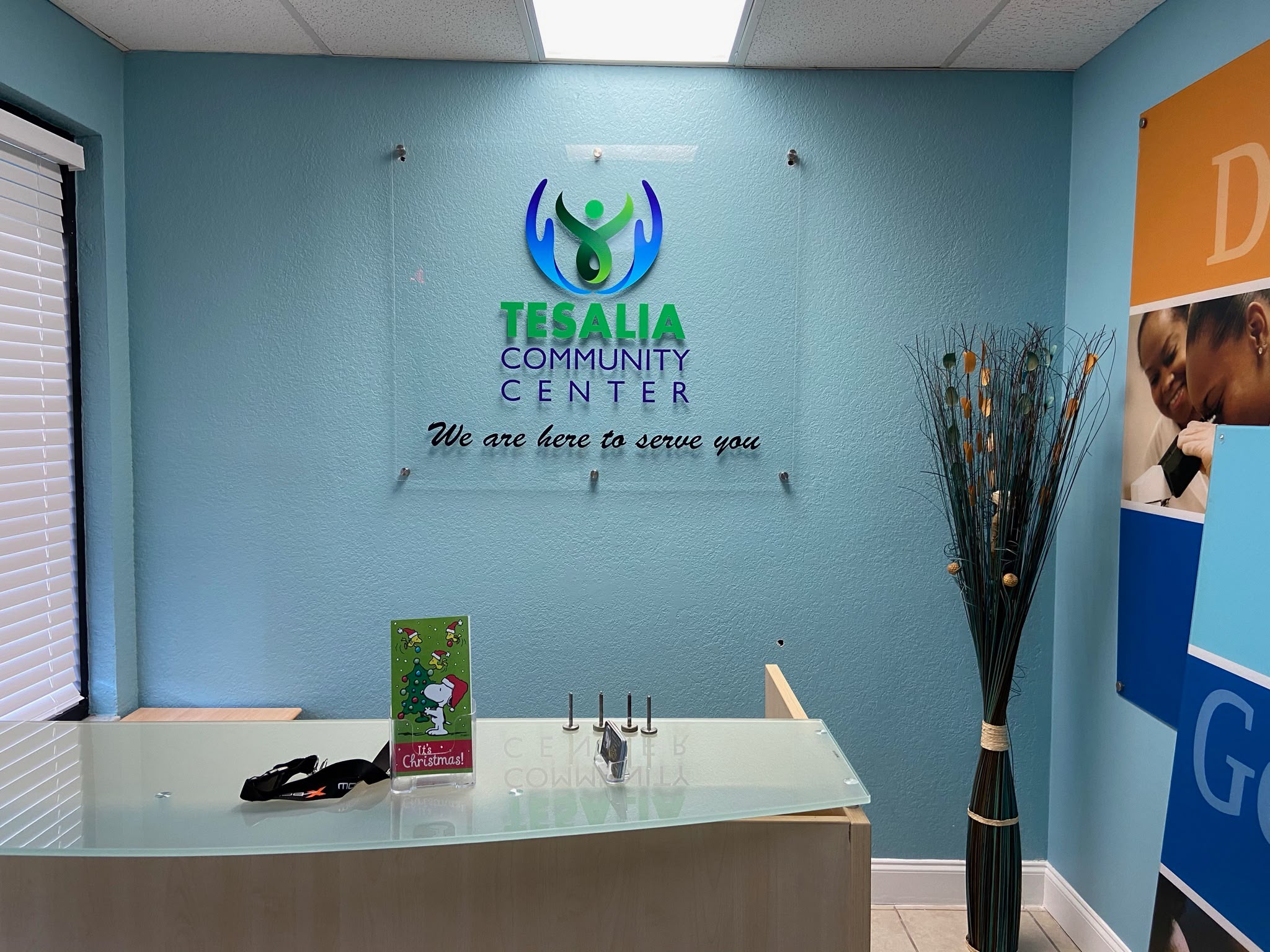 Tesalia Community Center clear acrylic lobby sign with dimensional logo and standoff mounts on teal accent wall in Kendall FL