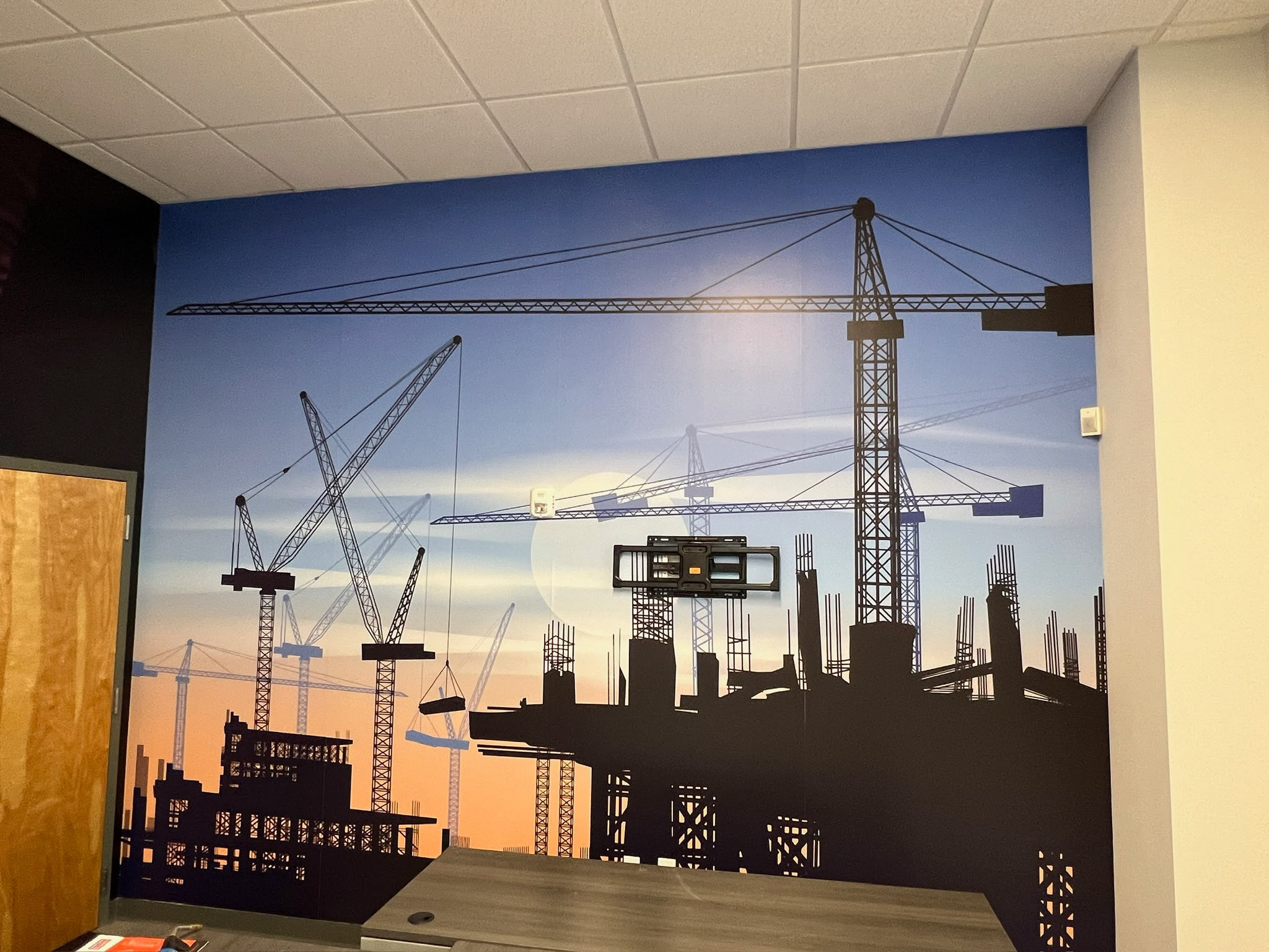 Corporate office feature wall wrap featuring architectural construction cranes silhouette sunset mural in Doral FL