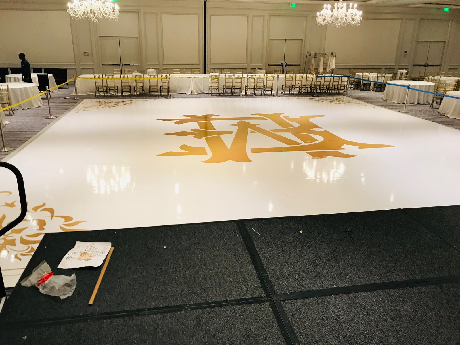 High-gloss white wedding dance floor wrap with gold crest monogram and corner accents in Miami Beach FL