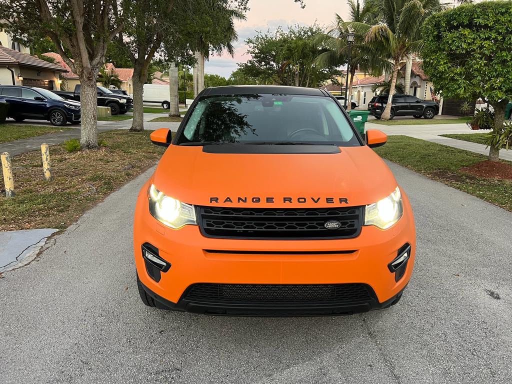 Front fascia view of Range Rover Discovery Sport wrapped in vibrant satin sunset orange with blacked-out trim by Specialized Wrapping Design
