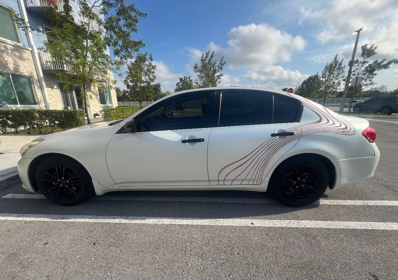 Side profile of pearl white luxury sports sedan with custom contoured rose line decals and gloss black wheels in Coral Gables FL