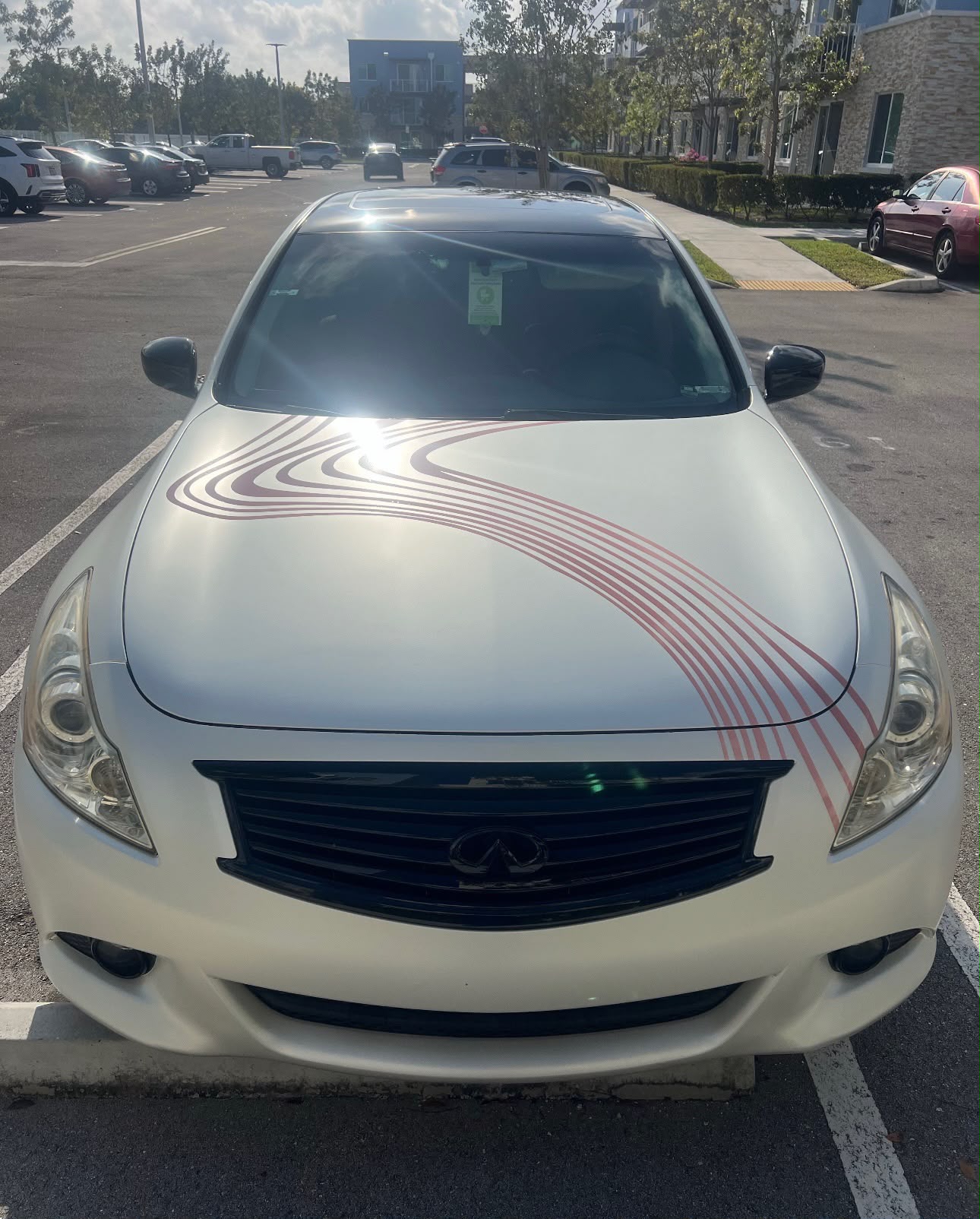 Front hood shot of white Infiniti sedan with custom red topographical wave contour line graphics in Coral Gables FL