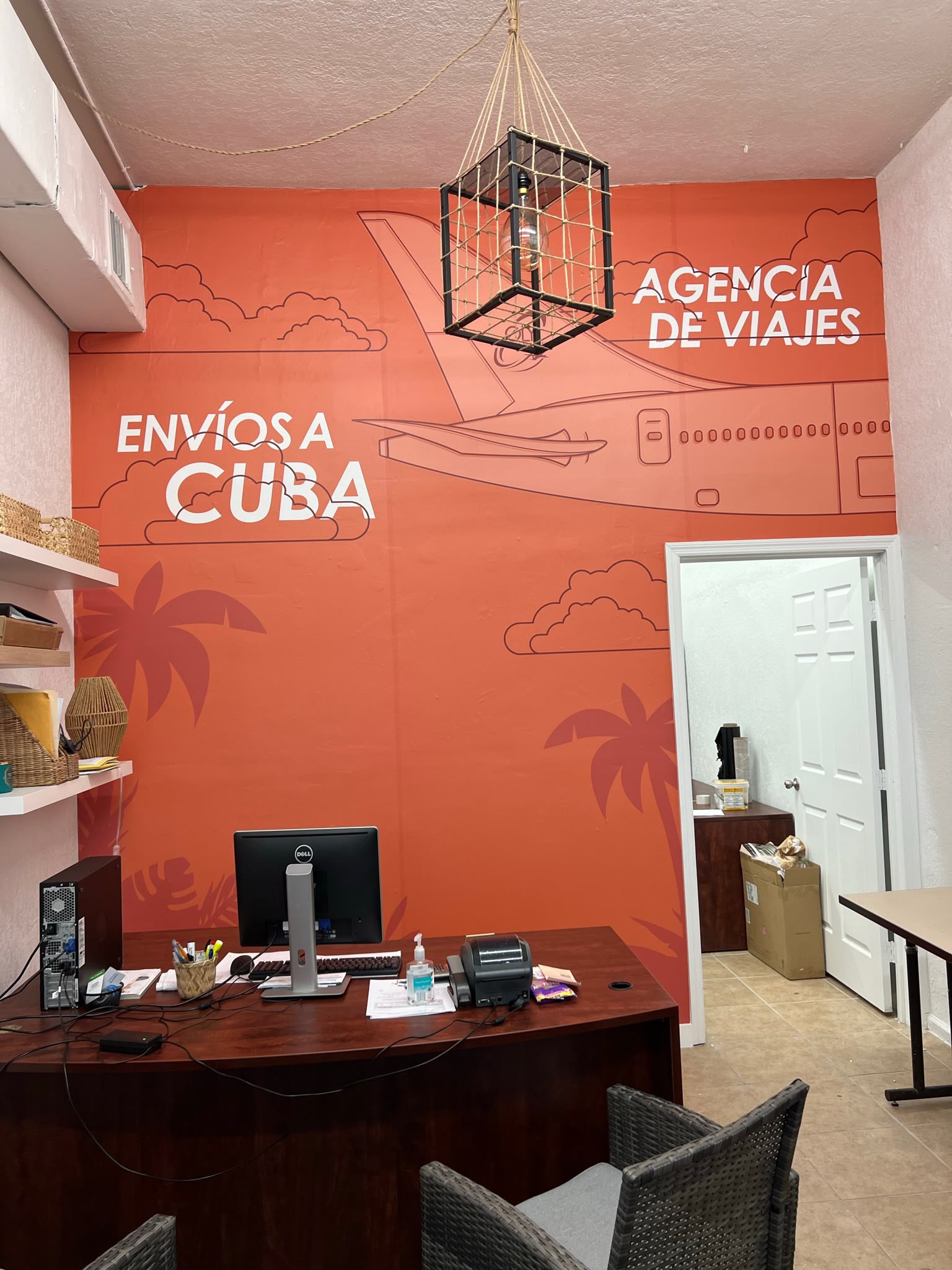 Envíos a Cuba and travel agency reception feature wall wrap in vibrant orange with airplane mural in Hialeah FL